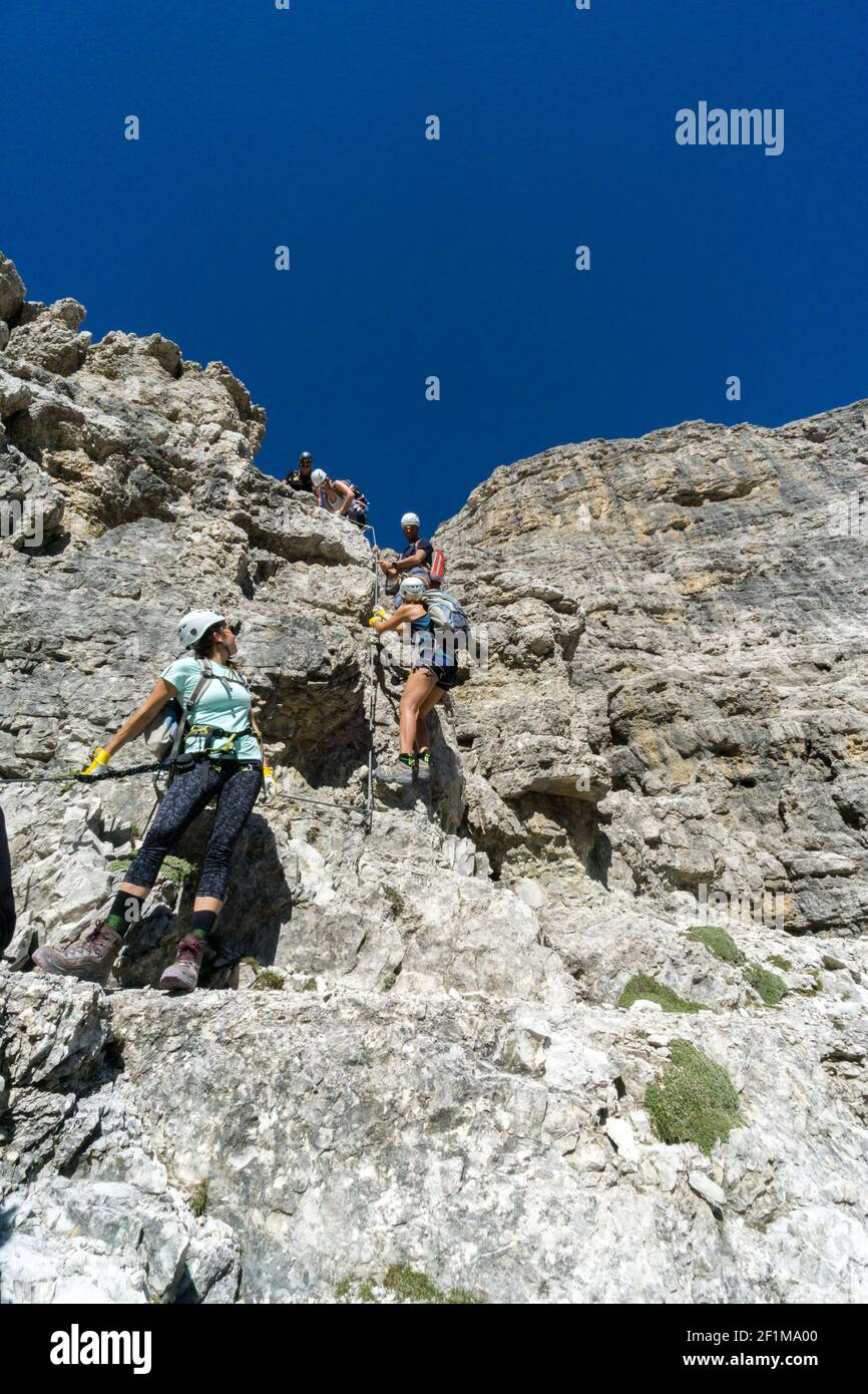 Bergführer und mehrere Kunden besteigen einen Klettersteig in Die italienischen Dolomiten Stockfoto