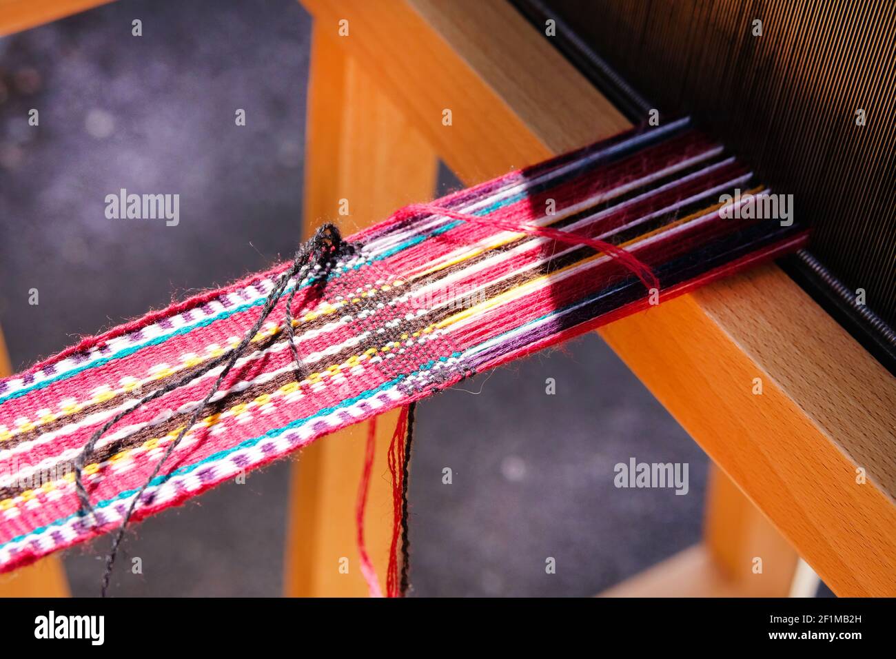 Nahaufnahme von mehrfarbigen Wollfäden auf dem traditionellen Webstuhl. Nationale Weberei Handwerk Konzept. Stockfoto