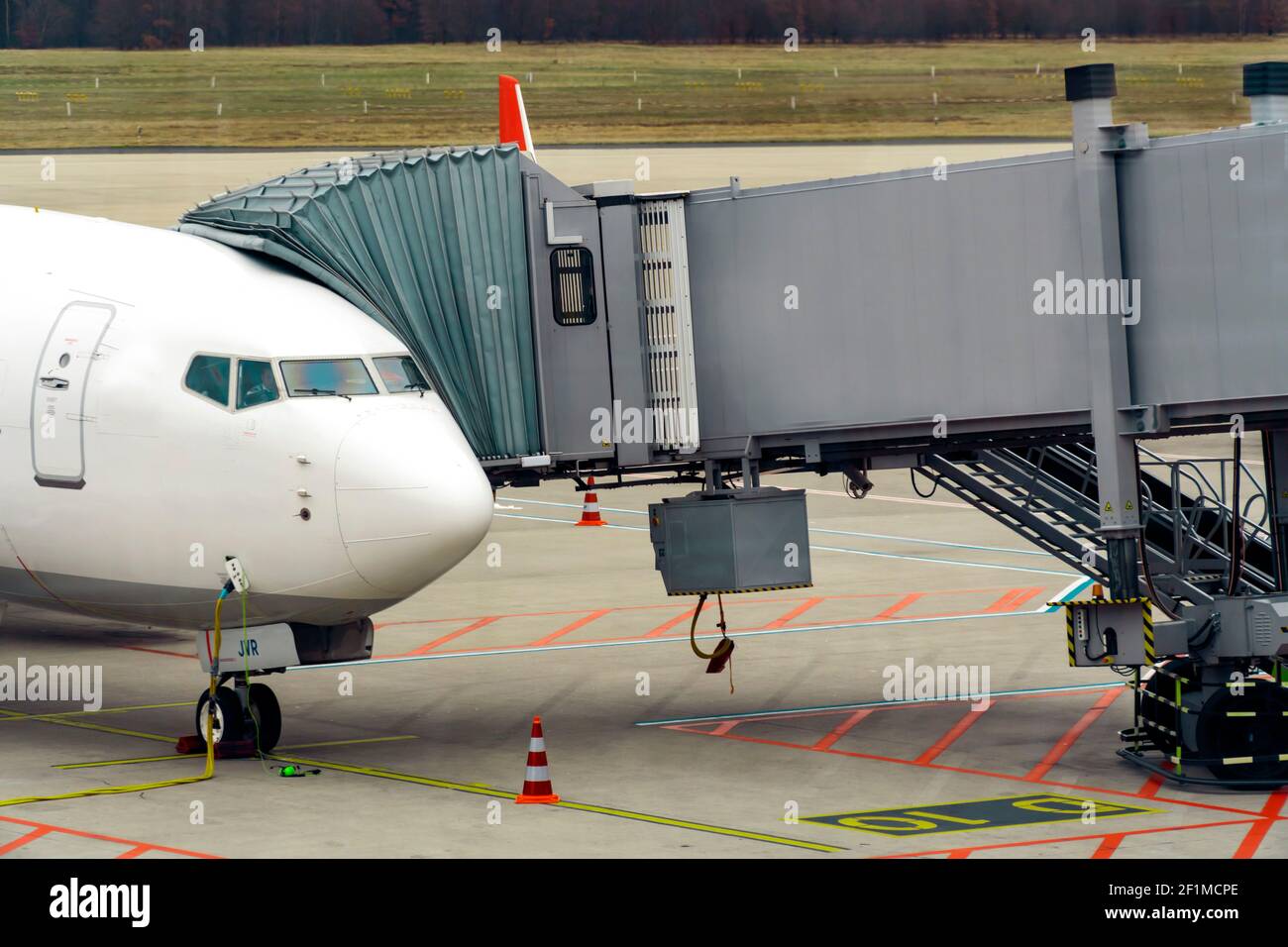 Reiseverbot aufgrund der Covid-19-Pandemie. Das Flugzeug dockte an die Jet Bridge an. Keine Marke. Vorderseite des Flugzeugs vom Gate andocken. Bereit für den Start. Luftfahrtkrise Stockfoto