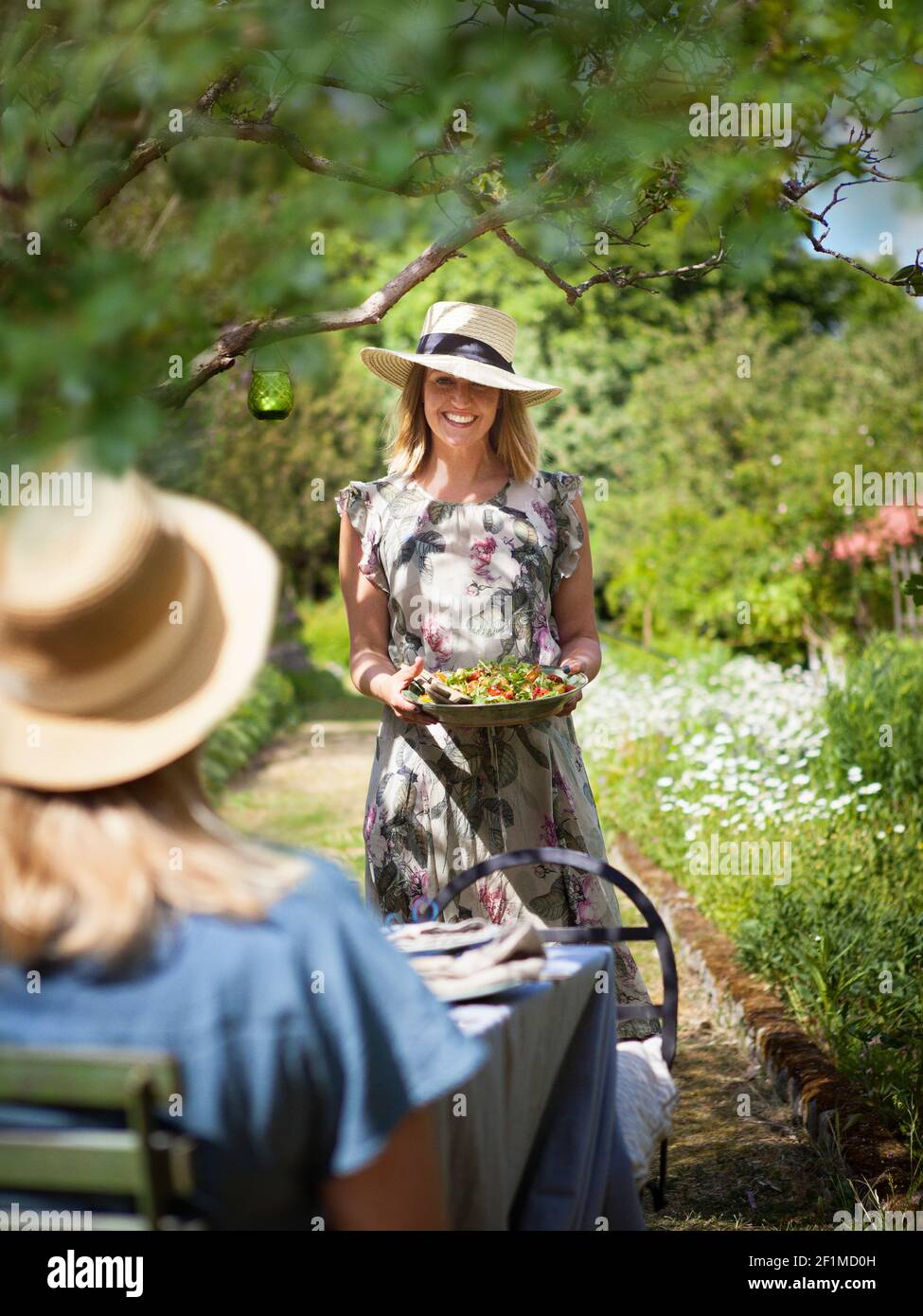 Lächelnde Frau im Garten hält Teller mit Essen Stockfoto