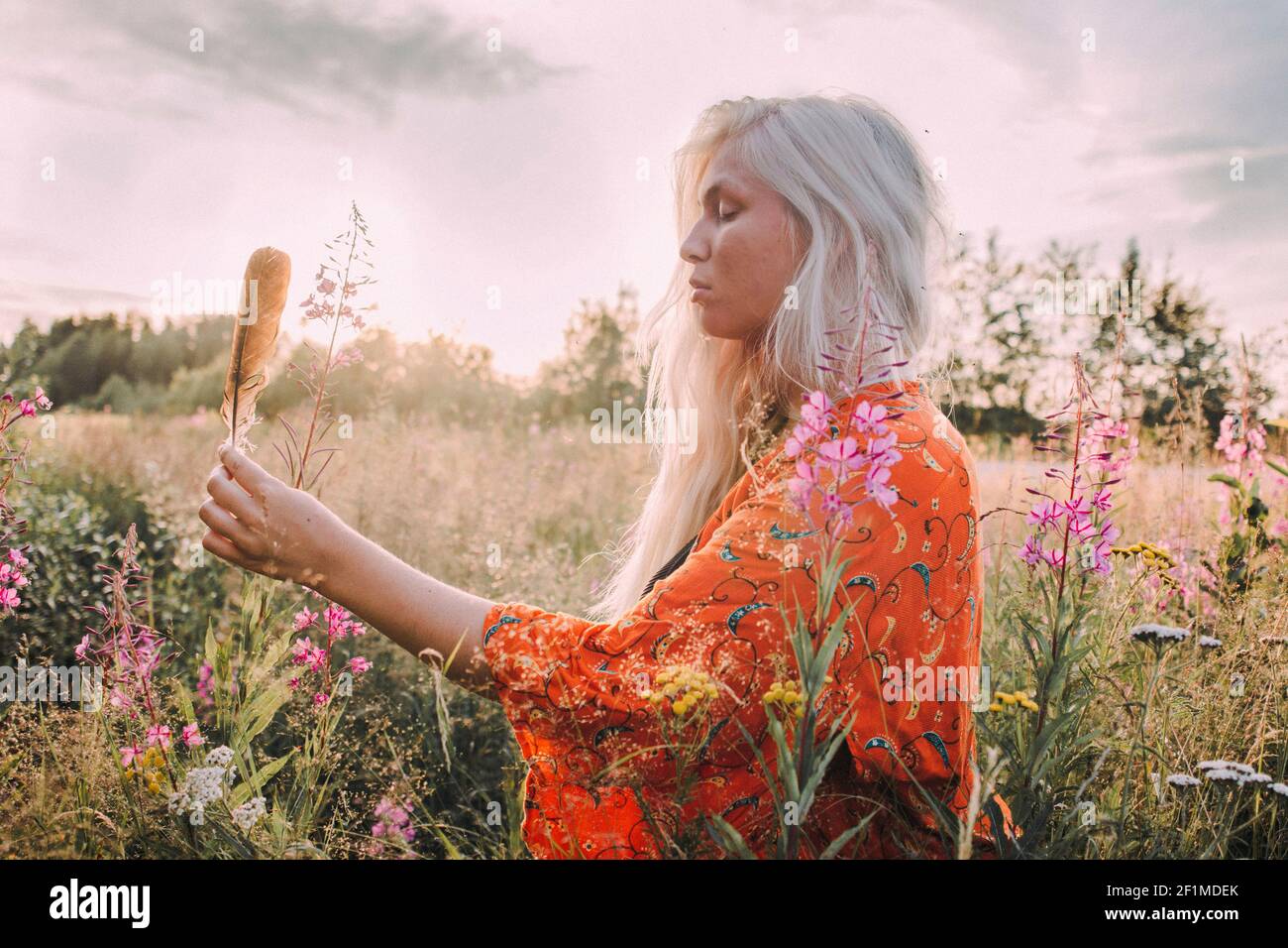 Junge Frau mit Feder auf der Wiese Stockfoto