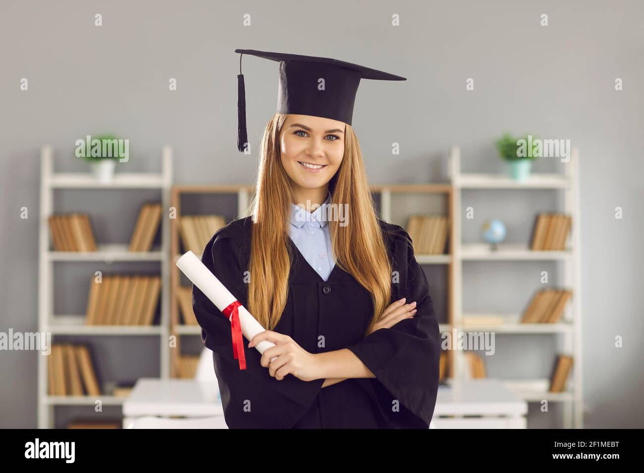 Studentin in Form eines Hochschulabsolventen und mit einem Diplom in ihren Händen. Stockfoto