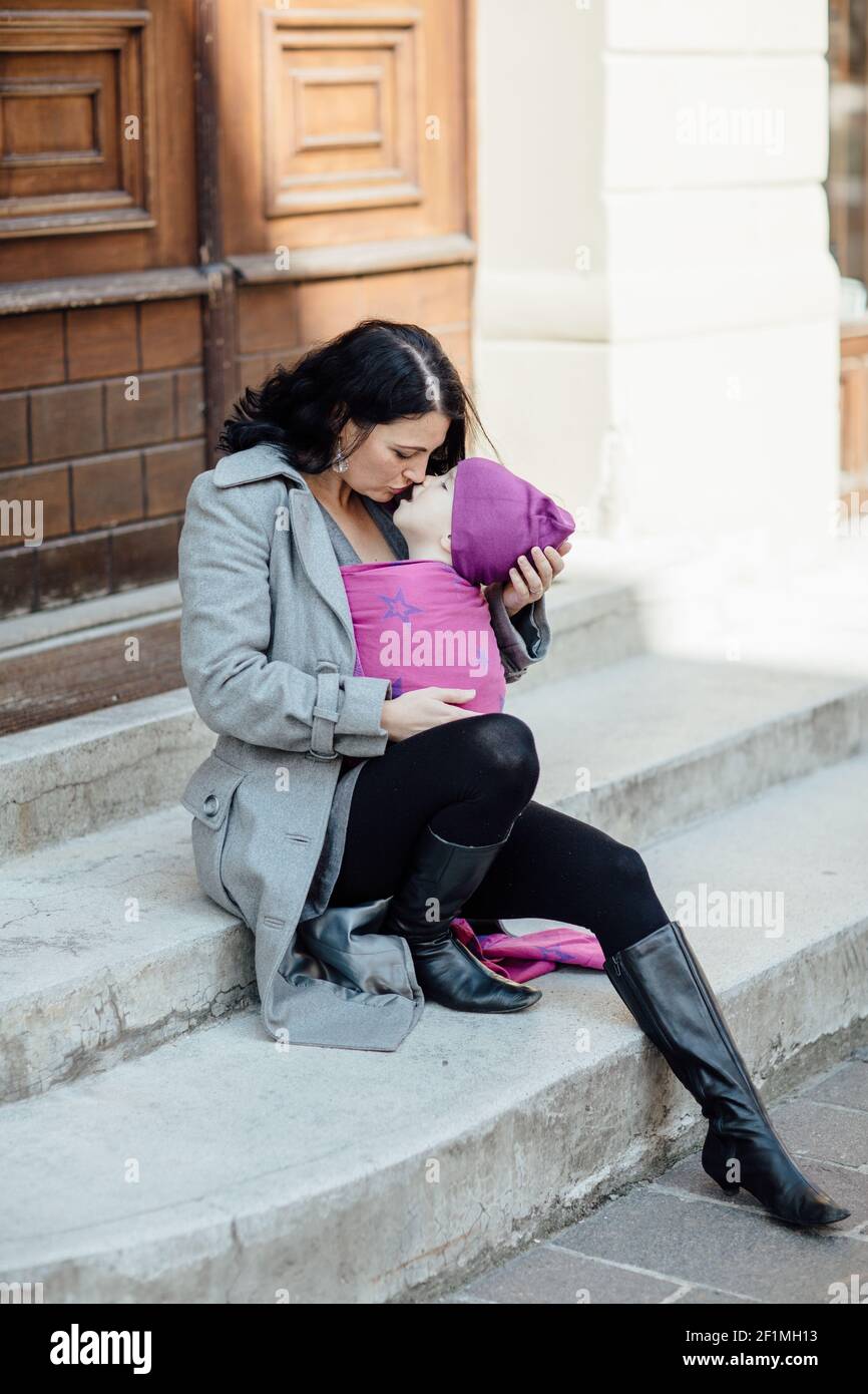 Portrait der liebevollen Babytragemutter trägt ihr Kind in der Stadt Stockfoto