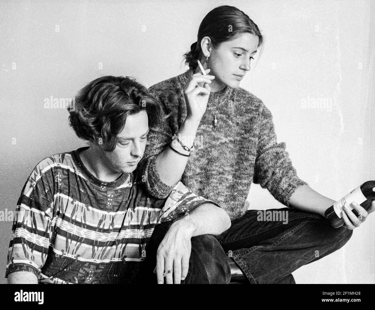 Tilburg, Niederlande. Junger Mann und junge Frau, die über eine Flasche roten Whines nachdenken, Studioportrait auf Analog Black & White Film, 1995. Stockfoto