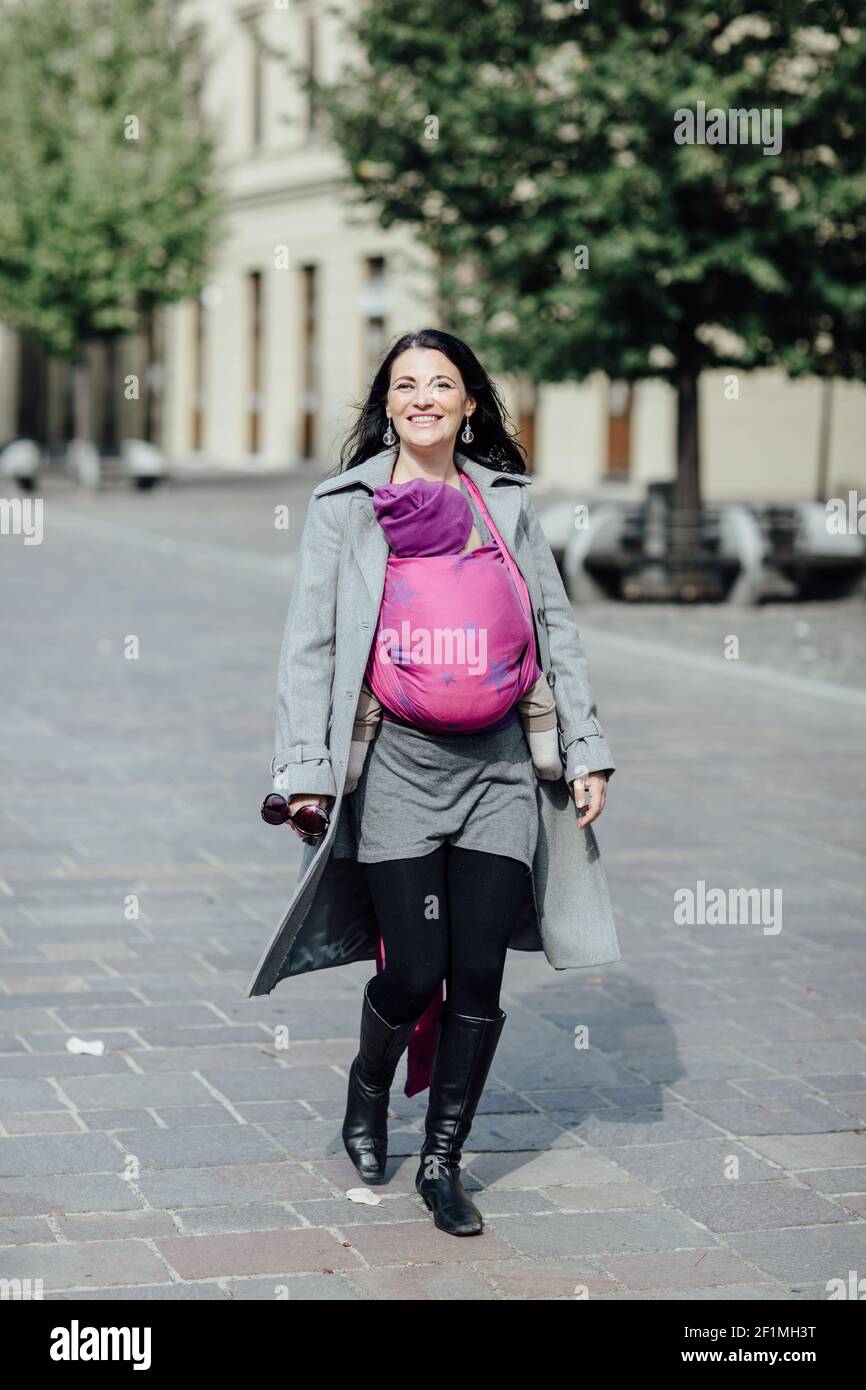 Portrait von glücklichen Babytragemutter trägt ihr Kind zu Fuß in Die Stadt Stockfoto