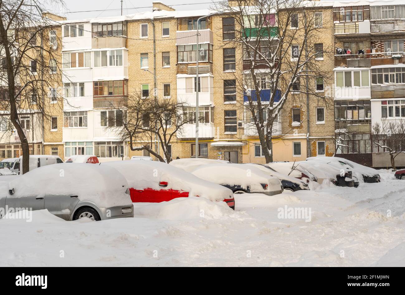 Stadtstraße nach Schneesturm. Autos unter Schnee und Eis stecken. Vergrabenes Fahrzeug in Schneewehe auf der Straße. Parkplätze im Winter nach starkem Schneefall Stockfoto