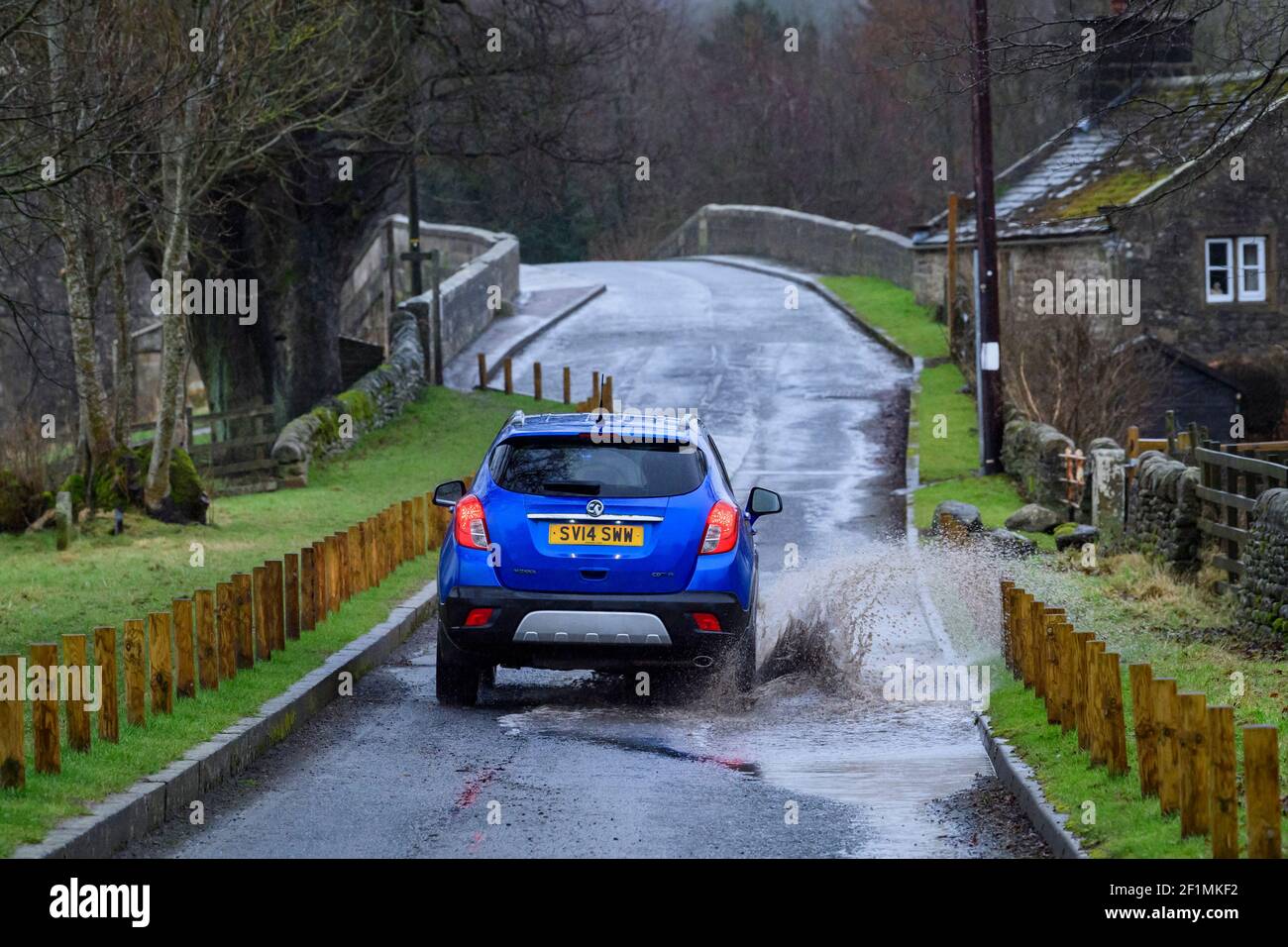 Vauxhall Mokka Auto unterwegs auf Landstraße durch Pfütze (Spritzwasser Spritzen Oberflächenwasser) an nassen Regentag - Bolton Bridge, Yorkshire, England, UK Stockfoto