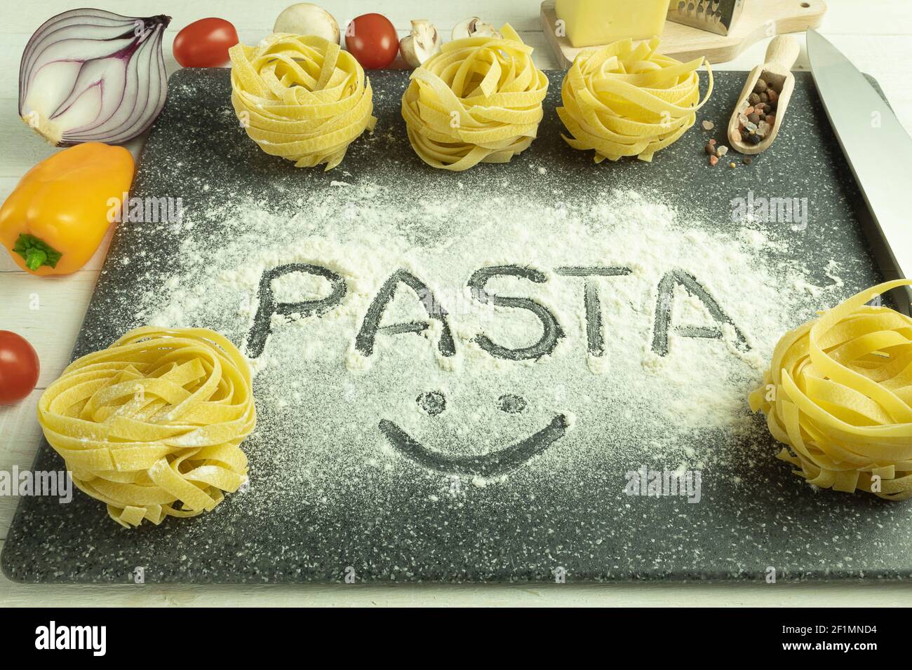 Das Wort Pasta auf einem Pasta-Hintergrund. Pasta Wort auf dem Tisch Zusammensetzung mit Zutaten geschrieben Stockfoto