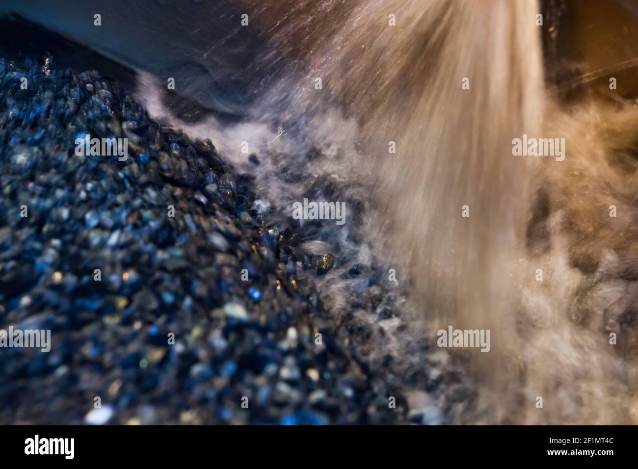 Unfokussierter industrieller Hintergrund. Graue Steine und Wasserstrahl.Waschen von Golderz auf konzentrierende Pflanze. Khromtau, Mechel, Kasachstan. Geringe Schärfentiefe. Stockfoto