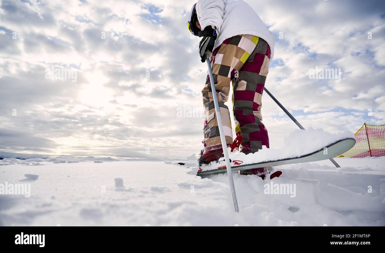 Nahaufnahme, Low-Angle-Ansicht Momentaufnahme der Beine des Skifahrers tragen bunte Skihose und weiße Jacke, machen Schritt vorwärts auf weißen schneebedeckten Oberfläche, Skitour. Speicherplatz kopieren. Konzept der Wintersport-Aktivitäten. Stockfoto