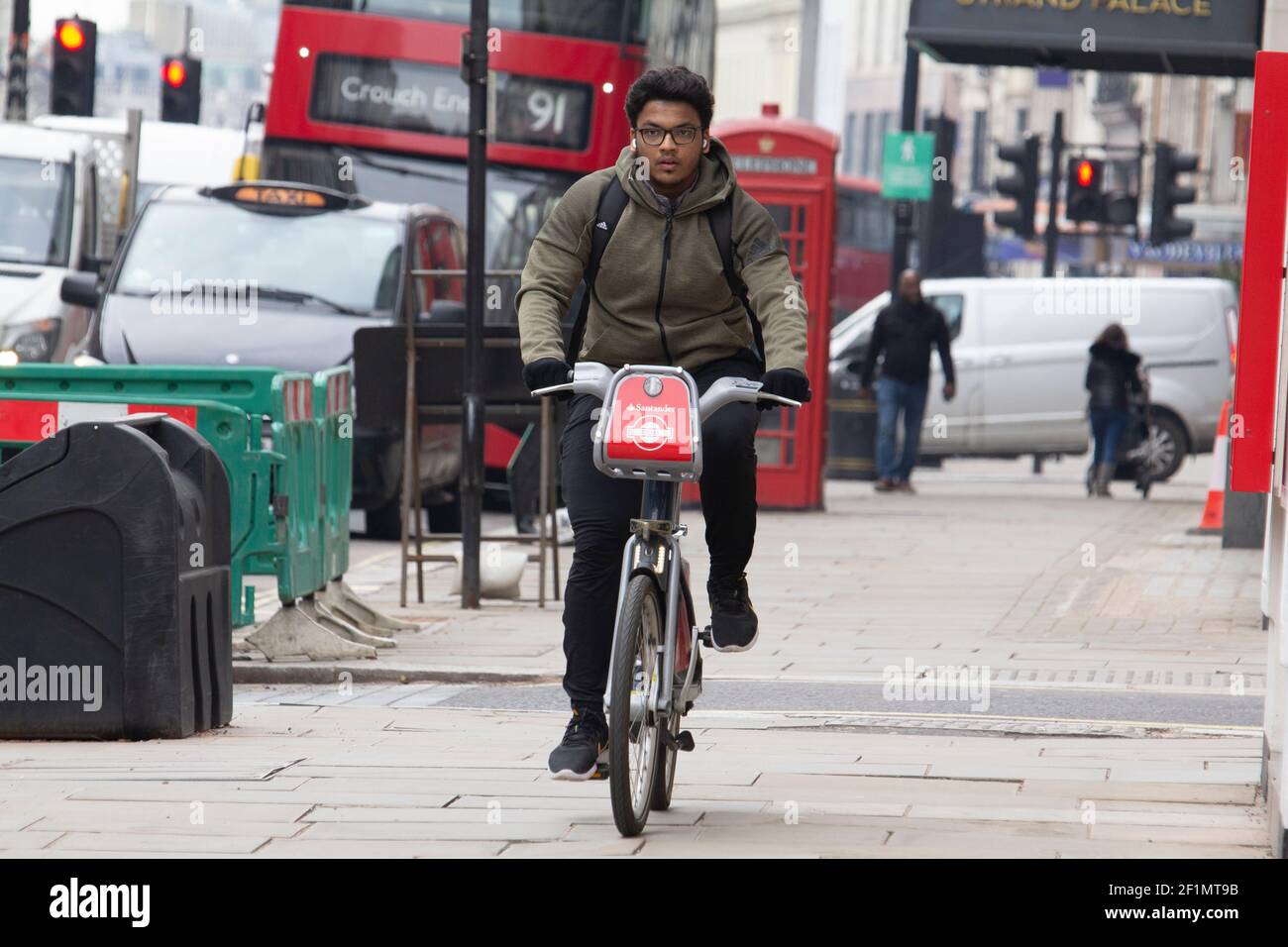 Männlich Reiten Santander mieten Fahrrad auf dem Bürgersteig der Strand London UK, während der Coronavirus, covid-19, Lockdown in England, Großbritannien, Stockfoto