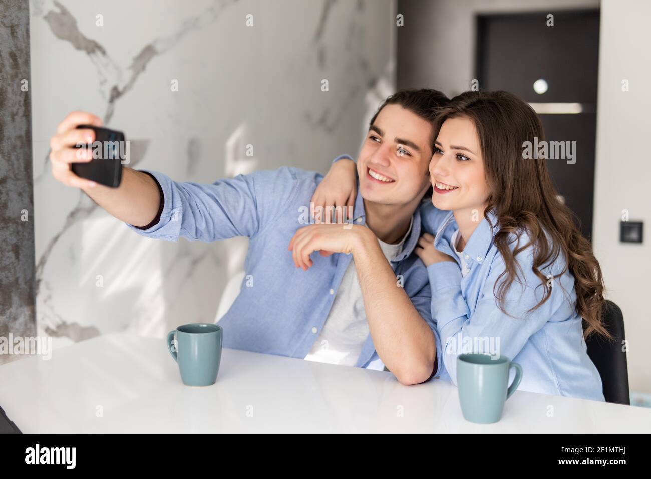 Millennial kaukasischen Mann und Frau sitzen zu Hause Küche sprechen auf  Videoanruf oder haben Webcam sprechen auf Smartphone. Junge Paar Ehepartner  verwenden Handy-Look Stockfotografie - Alamy