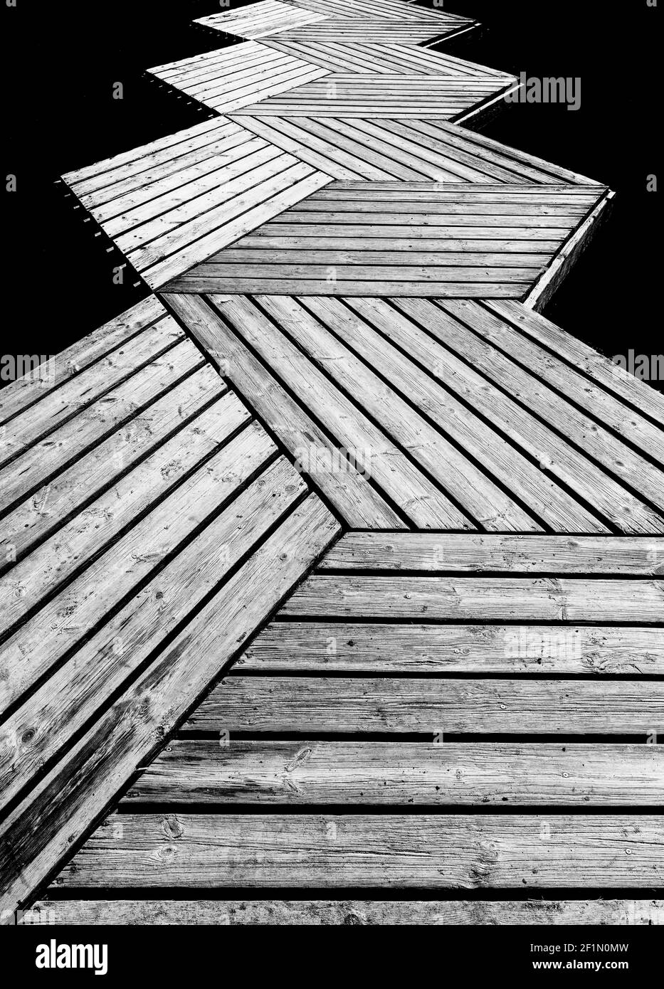 Eine Schwarz-Weiß-Low-Angle-abstrakte Ansicht eines Holzsteg und Pier, die in den Ozean führen Stockfoto