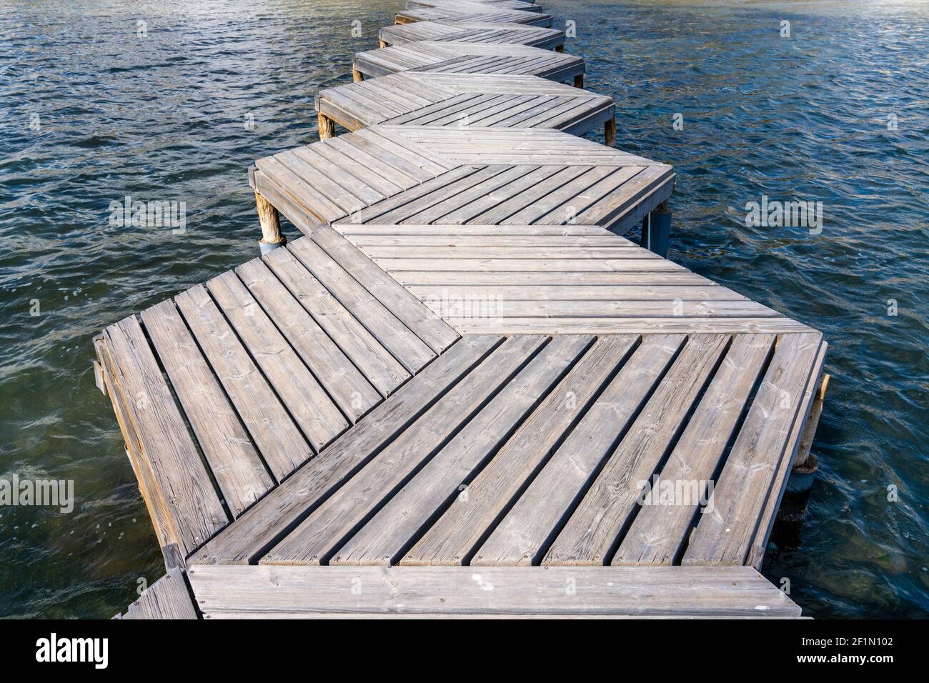 Eine Nahaufnahme aus einem tiefen Winkel abstrakte Ansicht eines Holzes Promenade und Pier, die in den Ozean führen Stockfoto
