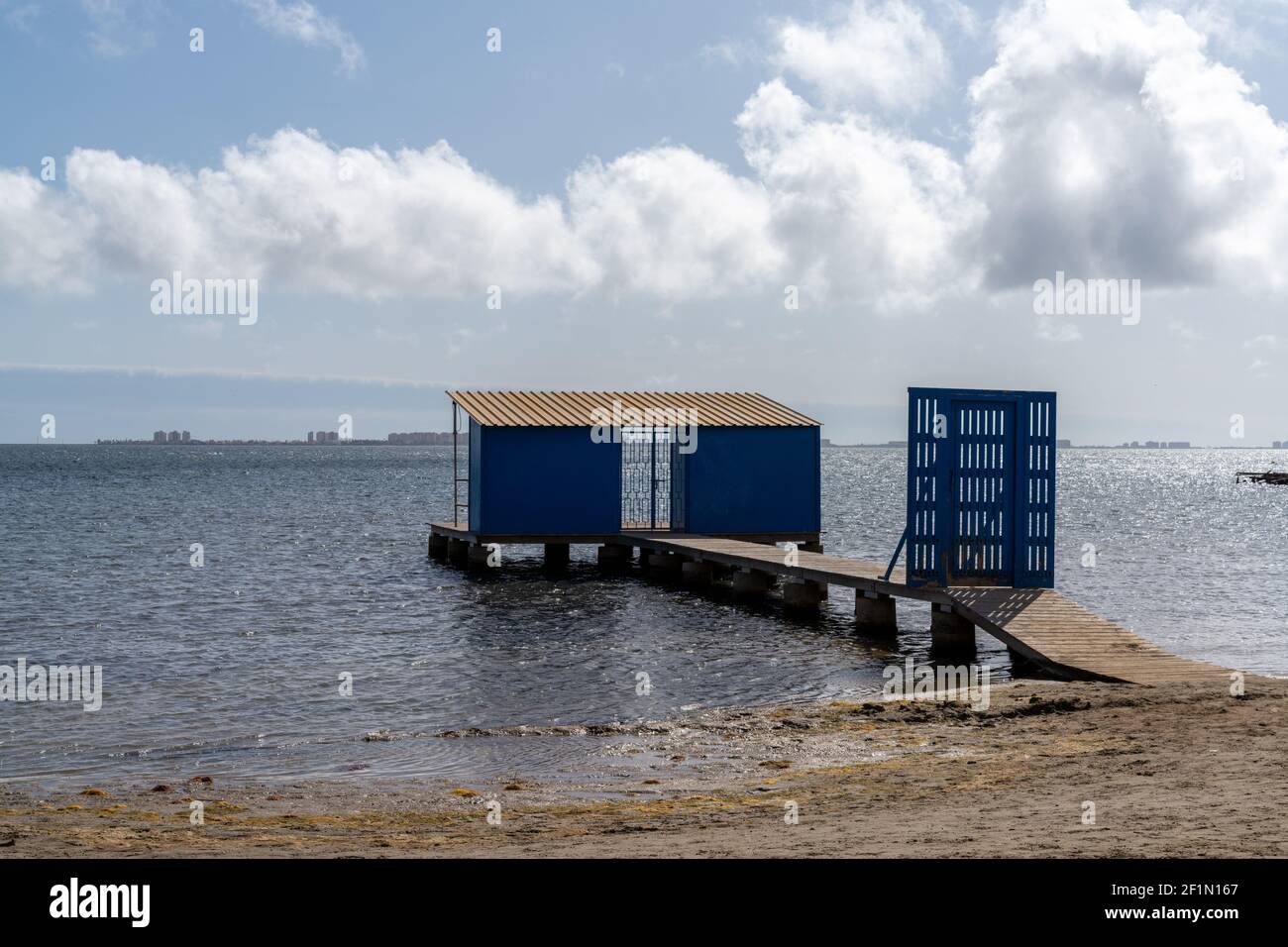 Eine Holzpromenade führt zu einer blauen Fischerhütte Auf dem Meer Stockfoto