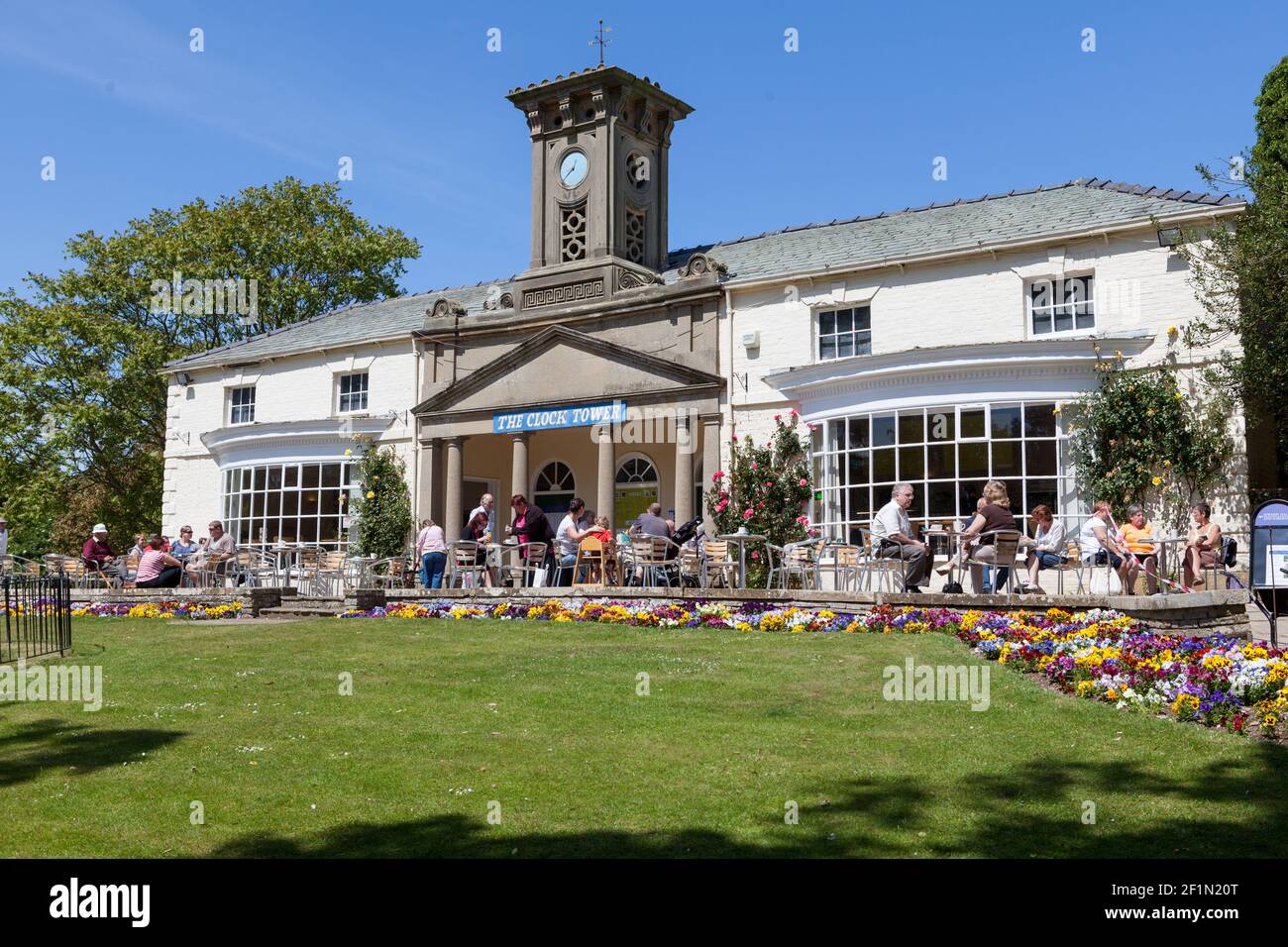 Besucher sitzen im Sonnenschein vor dem Clock Tower Cafe in Sewerby Hall in der Nähe von Bridlington, East Yorkshire Stockfoto