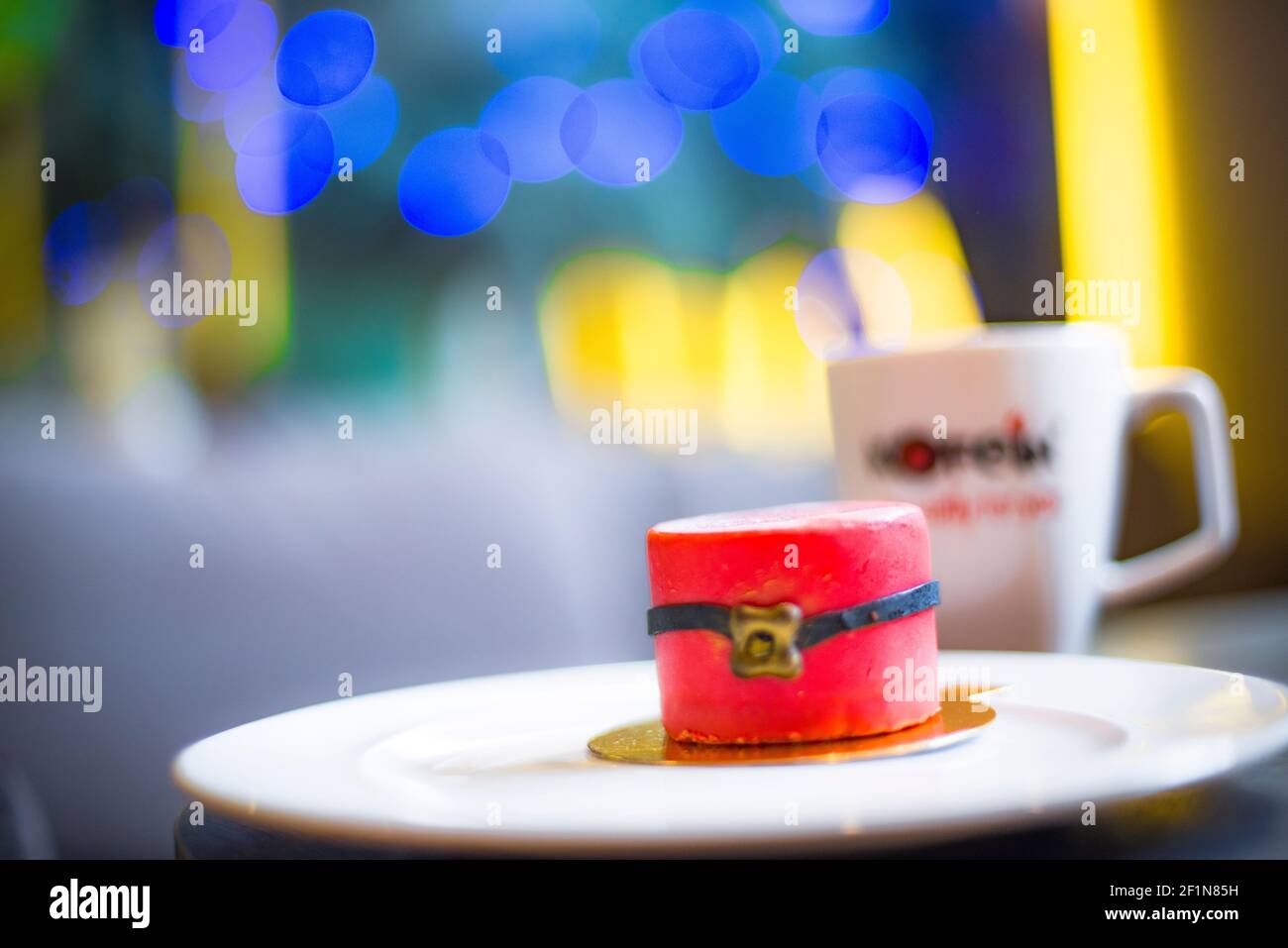 Eine kerzenartige Torte, für die Weihnachtszeit mit einer Tasse im Hintergrund Stockfoto