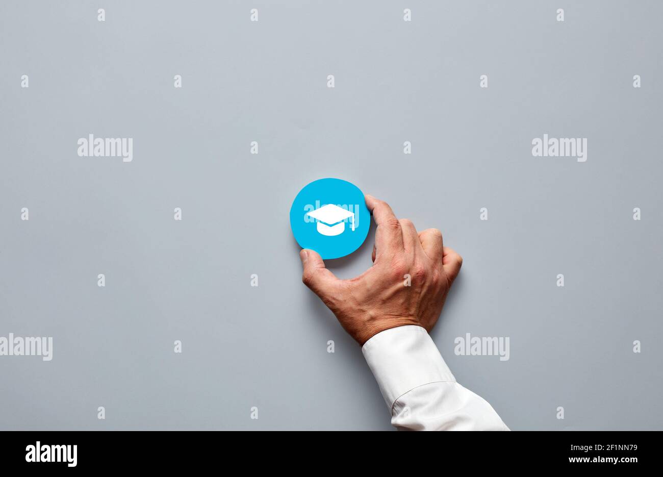 Businessman Hand hält ein blaues Abzeichen mit einem Abschlusskappe Symbol. Akademischer Grad Leistung oder Bewerbung Anforderungskonzept. Stockfoto
