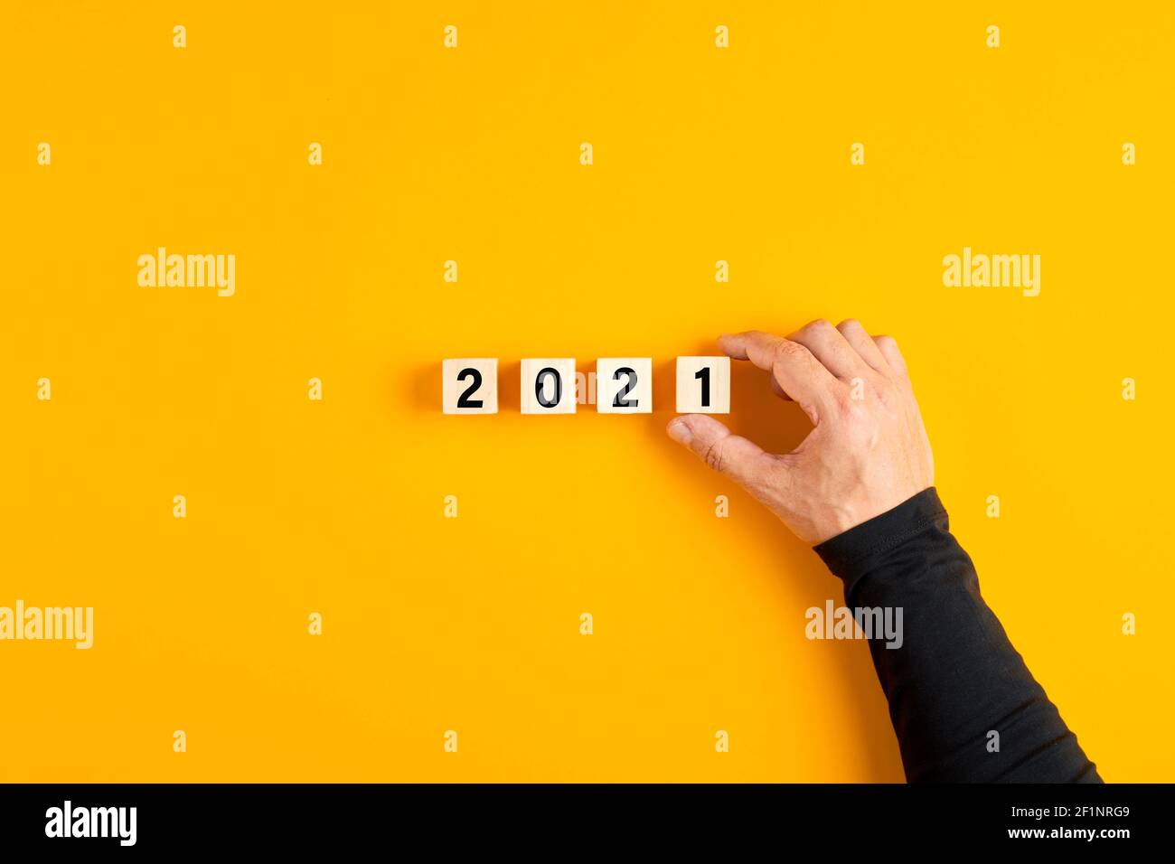 Männliche Hand, die einen Holzwürfel mit der Nummer eins platziert und das Jahr 2021 vollendet. 2021 Neujahresplanung oder Geschäftsziele Konzept. Stockfoto
