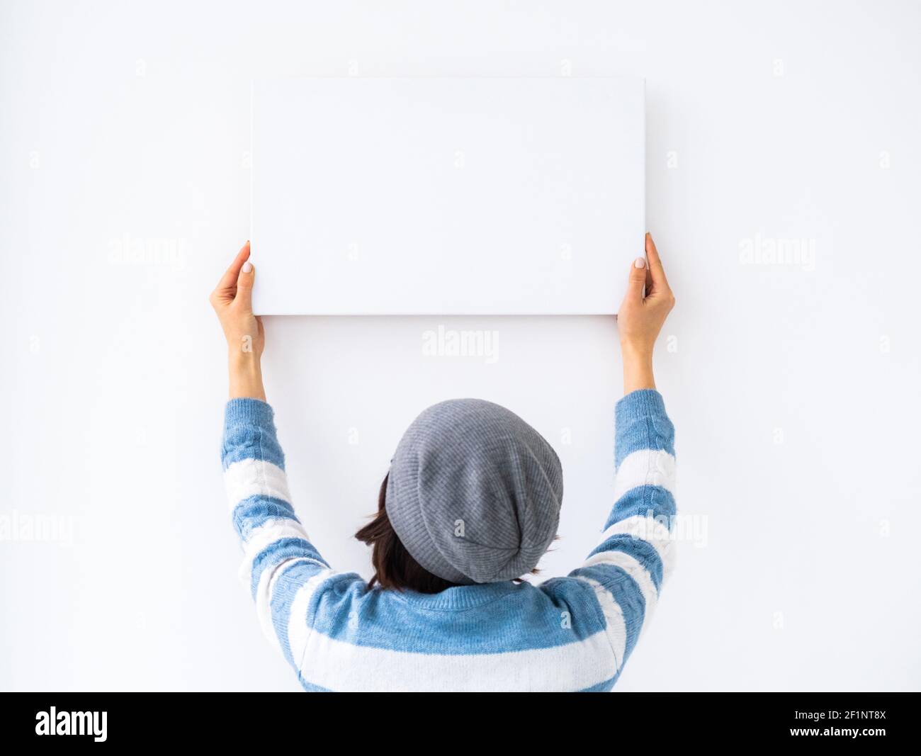 Mädchen hängen weiße Leinwand an der Wand Stockfoto