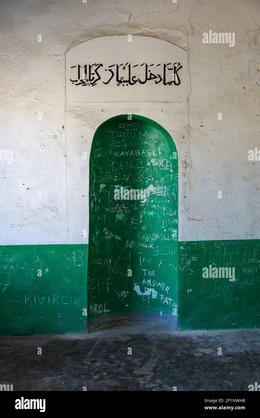 Eine grüne Nische an einer weißen Wand in einer islamischen muslimischen Moschee. Arabischer Text in schwarzen Buchstaben geschrieben Stockfoto