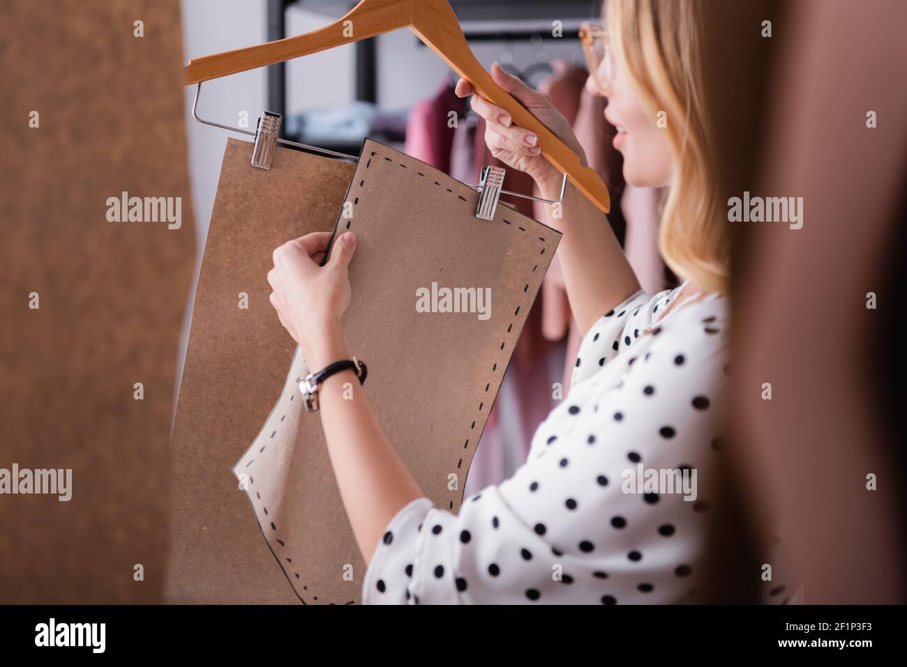Showroom Inhaber hält Kleiderbügel mit Vorlagen auf verschwommenem Vordergrund Stockfoto