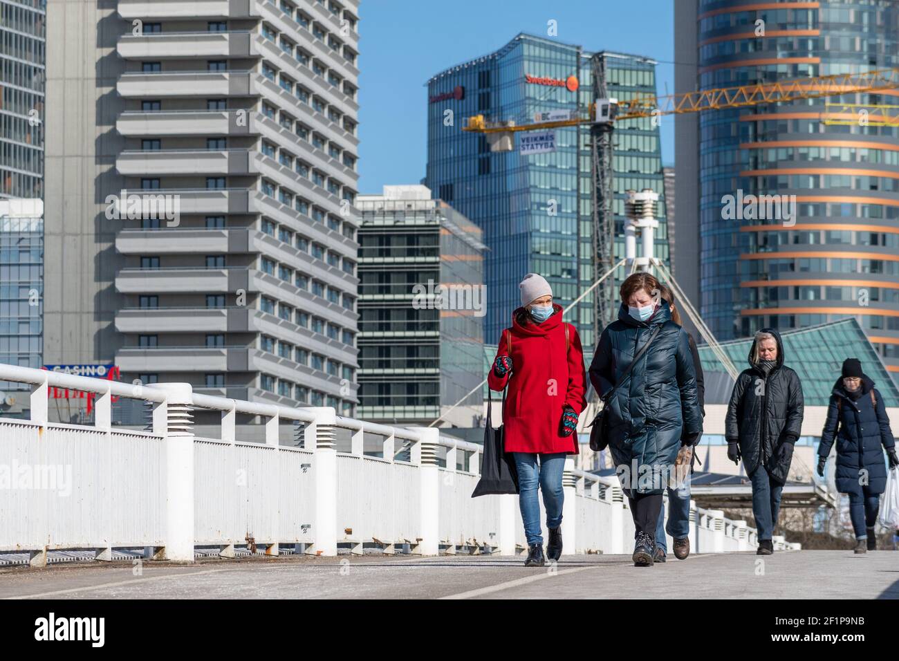 Mädchen oder Frauen, die während eines Covid- oder Coronavirus-Notfalls mit Maske laufen, Stadt, Gebäude und Wolkenkratzer im Hintergrund Stockfoto