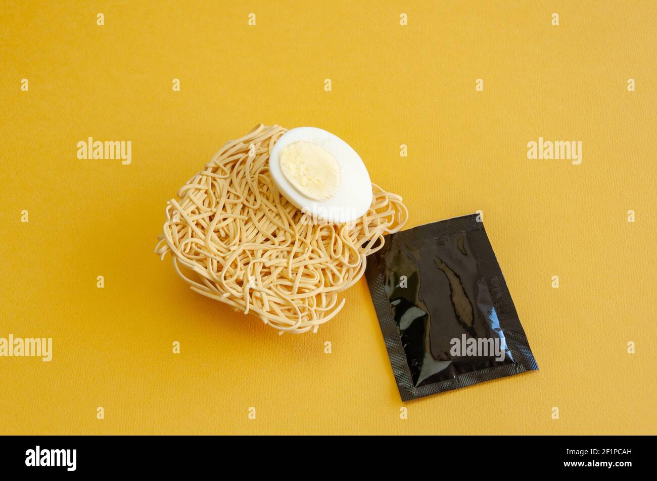 Nahaufnahme von gekochtem Ei auf Instant-Nudel auf gelbem Hintergrund. Leere Etikettenschachette Stockfoto