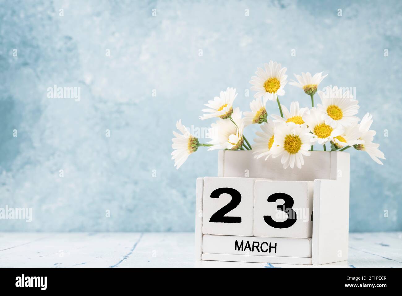 White Cube Kalender für märz mit Gänseblümchen über geschmückt Blauer Hintergrund mit Kopierbereich Stockfoto