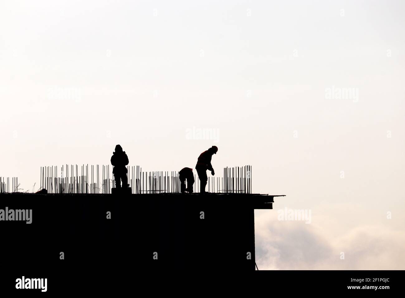 Silhouetten von Arbeitern auf der Baustelle gegen den Himmel. Wohnungsbau, Bauherren arbeiten auf Gerüsten Stockfoto