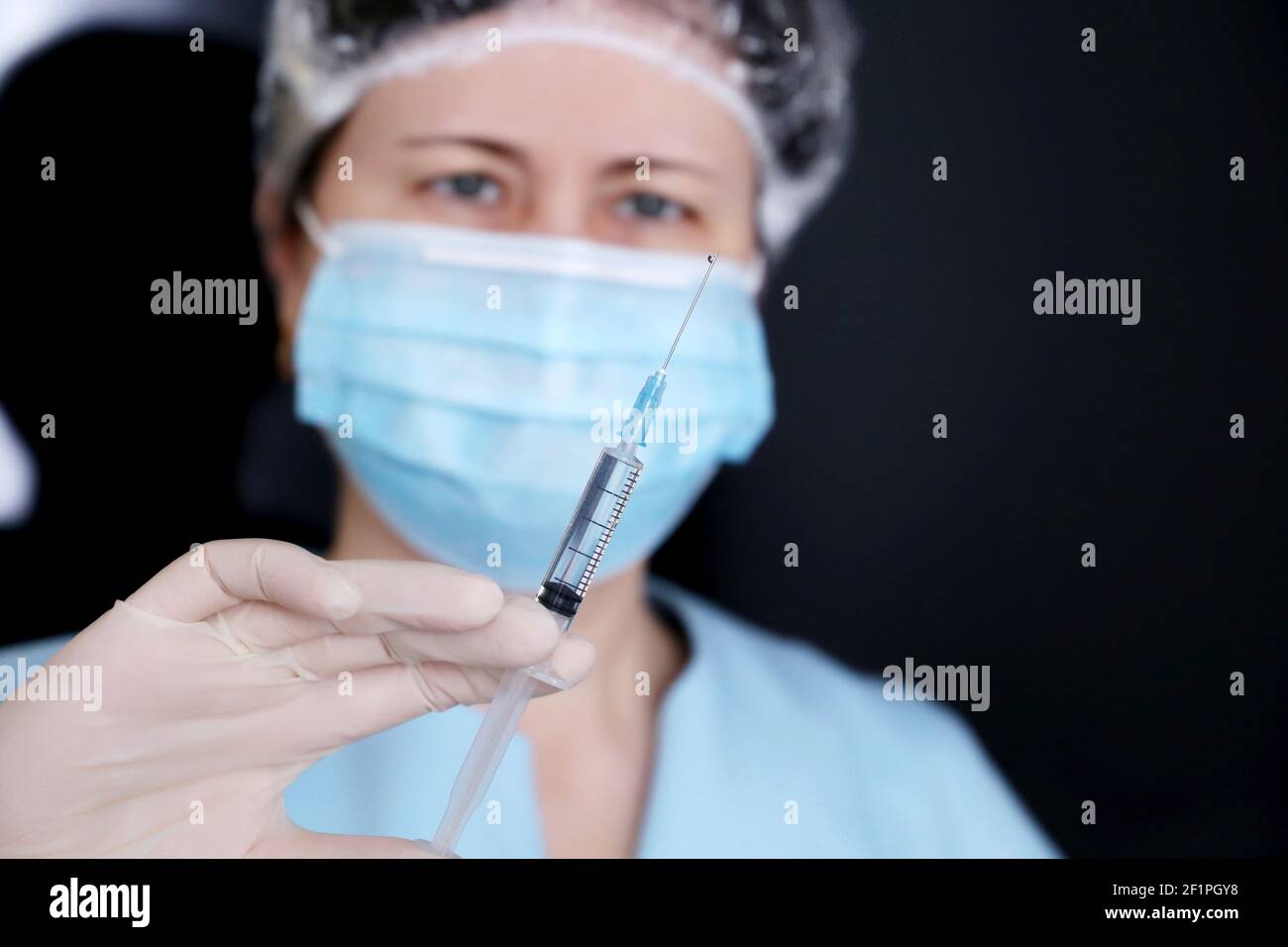 Arzt mit Spritze, Frau in medizinische Maske und Schutzhandschuhe Vorbereitung auf die Injektion. Konzept der Impfung während der Covid-19-Pandemie Stockfoto