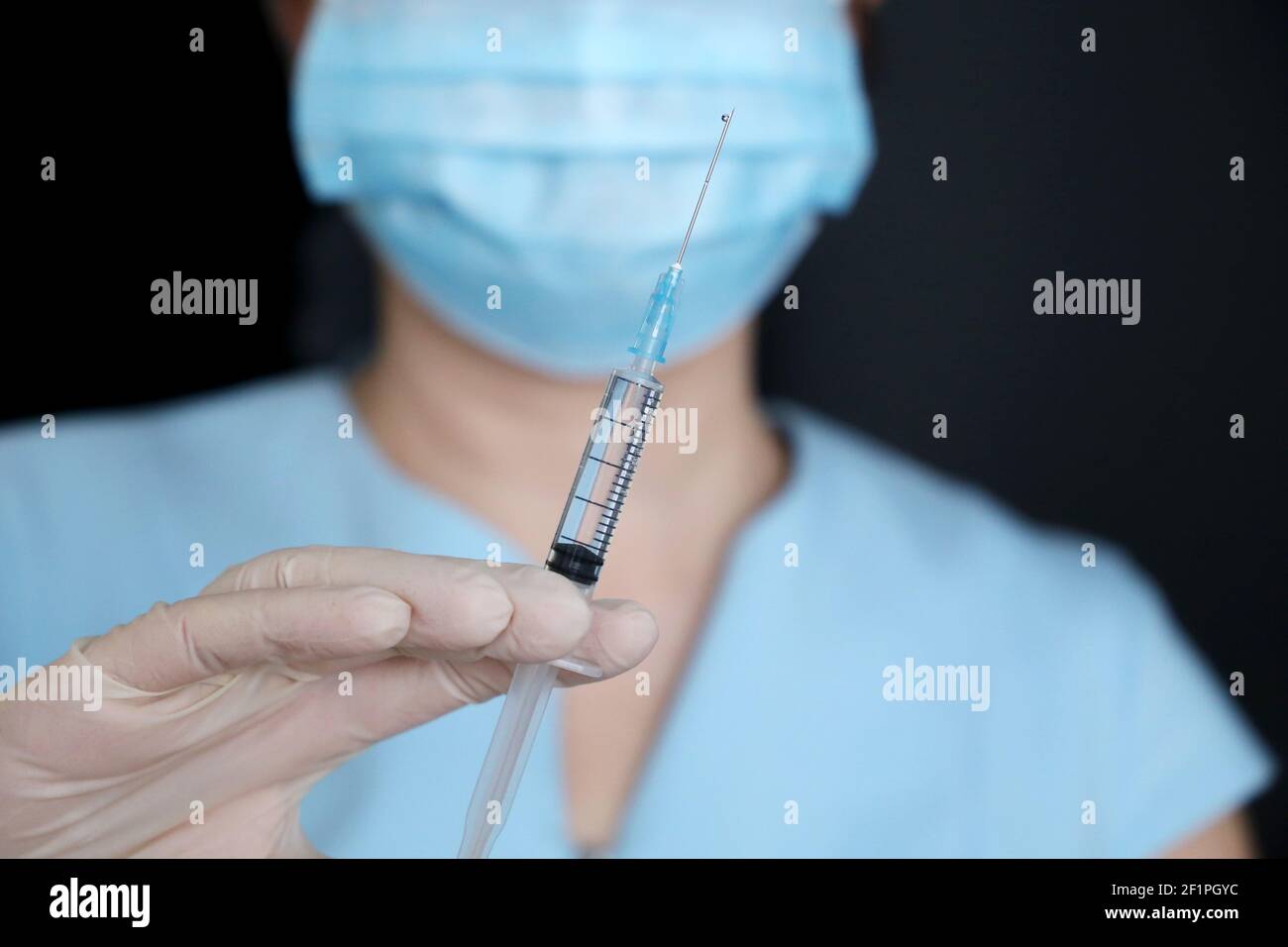 Krankenschwester mit Spritze, Frau in medizinische Maske und Schutzhandschuhe Vorbereitung auf die Injektion. Konzept der Impfung während der Covid-19-Pandemie Stockfoto