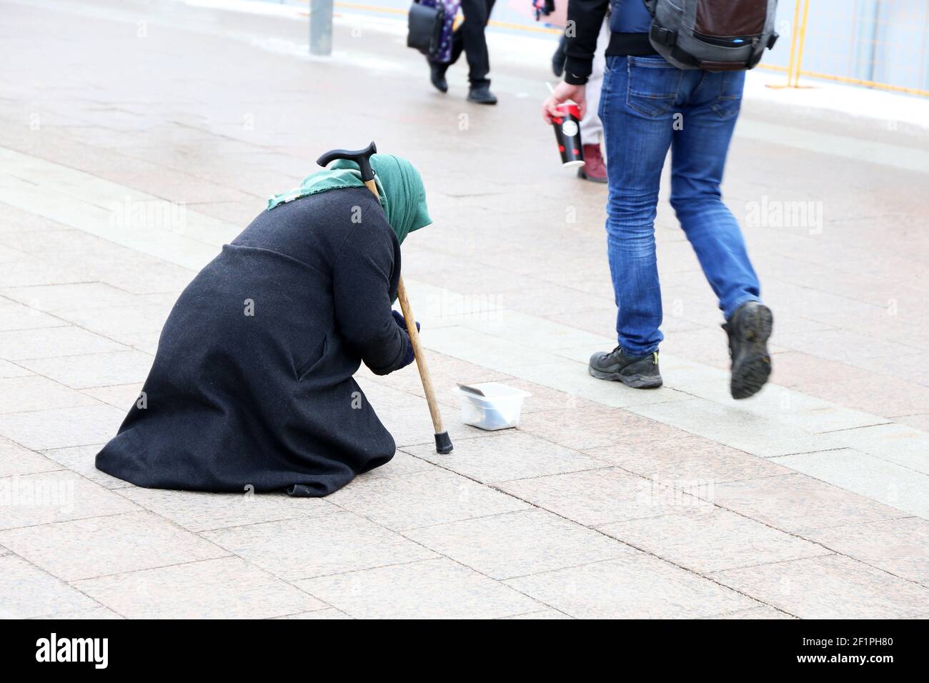 Die Bettelalte Frau bittet um Almosen, die auf einer Stadtstraße sitzen. Armut, Obdachlosigkeit und Bettelkonzept Stockfoto