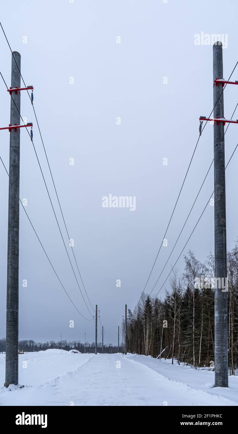 Hochbetonmasten von Hochspannungsleitungen auf Schnee Hintergrund Stockfoto