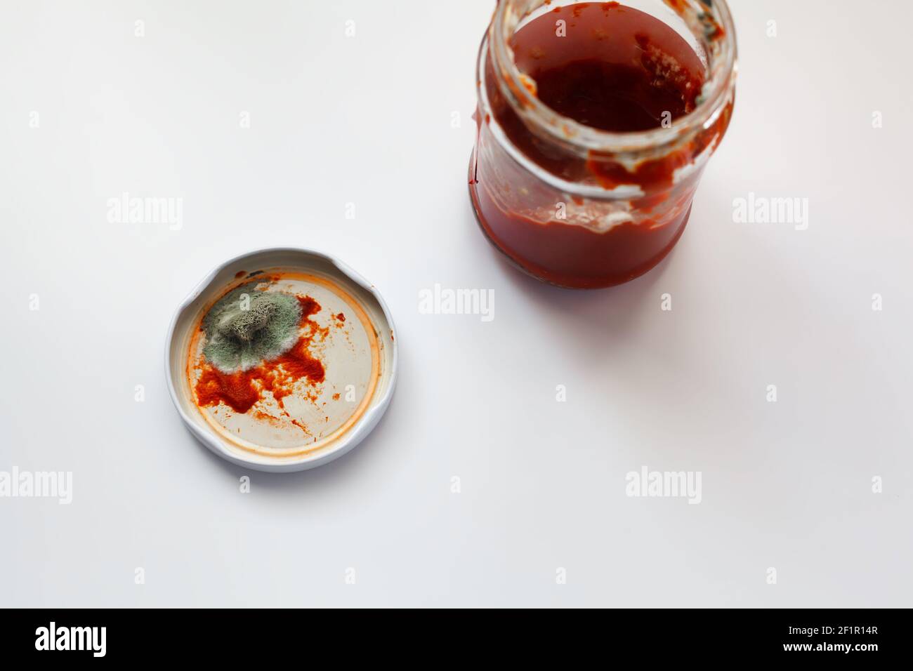 Öffnen Sie das Tomatenmark-Glas mit grüner Form auf einem Deckel. Minderwertige Lebensmittel. Verwöhnte Sauce Stockfoto
