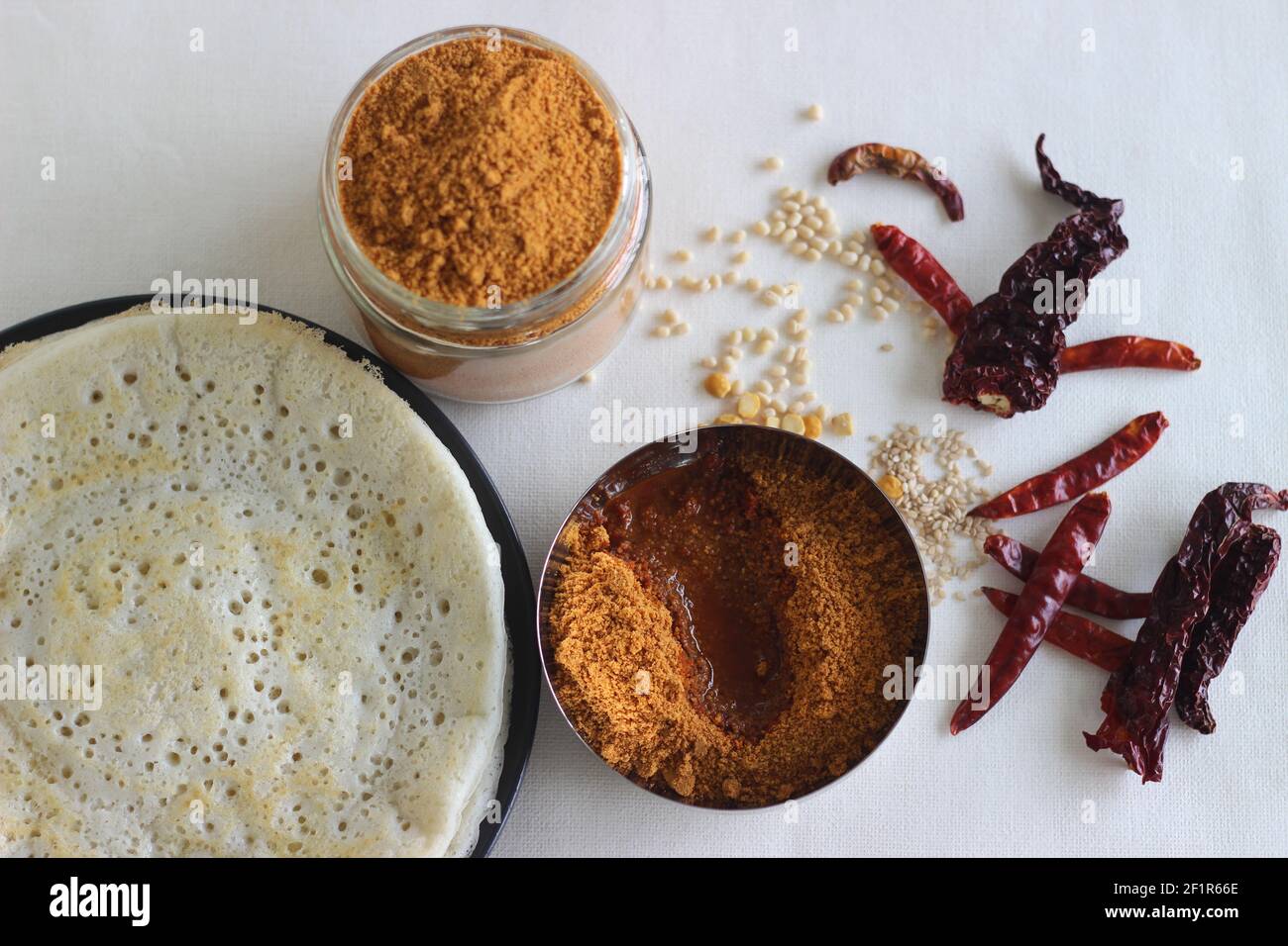 Indische Pfannkuchen werden auch als Dosa mit einem fermentierten Teig aus Reis und Linsen gemacht bekannt. Serviert mit idli podi chutney, sambar, Coconut Chutney und einem Glas Stockfoto