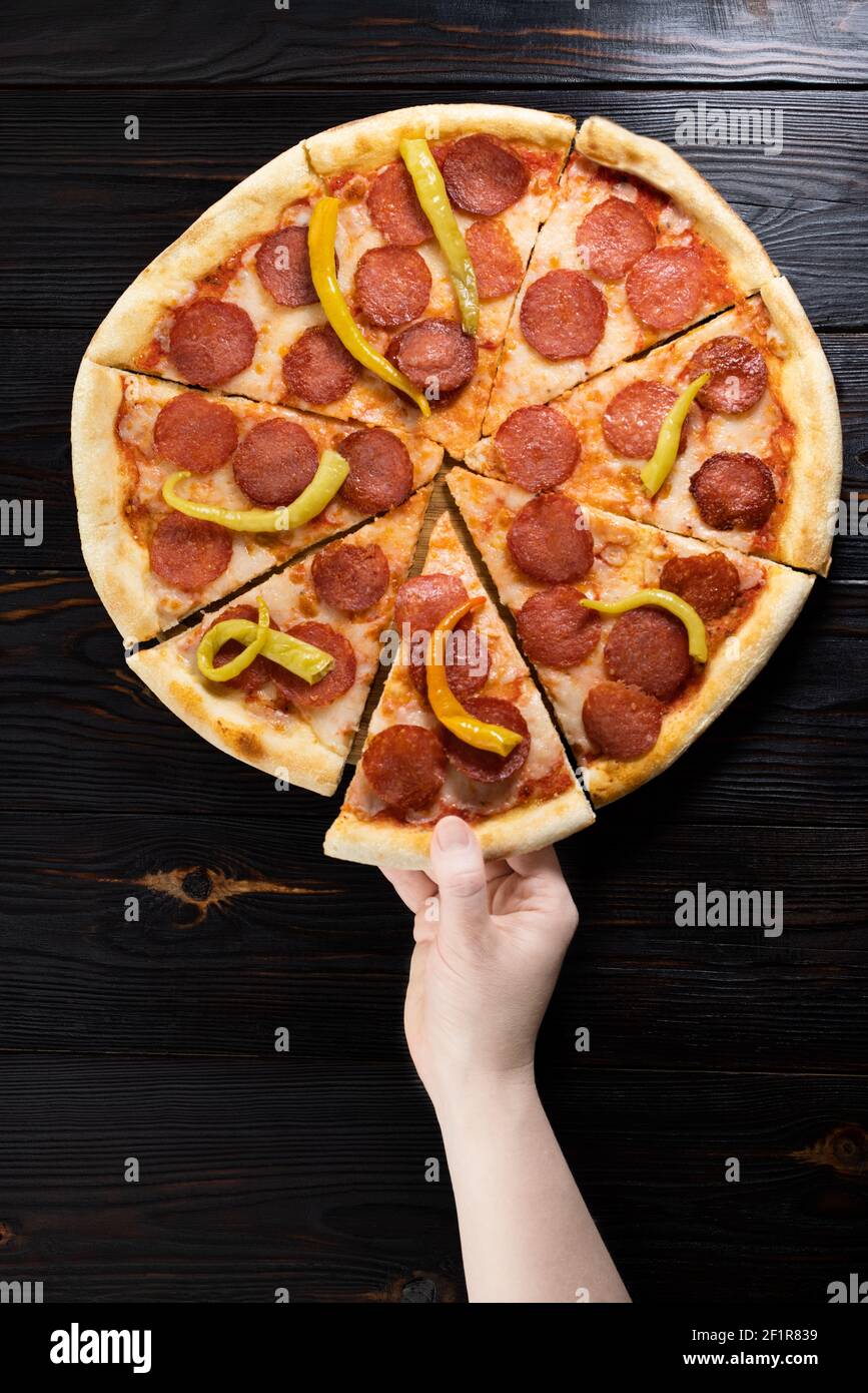 Die Hand der Frau nimmt ein Stück Pizza. Stockfoto