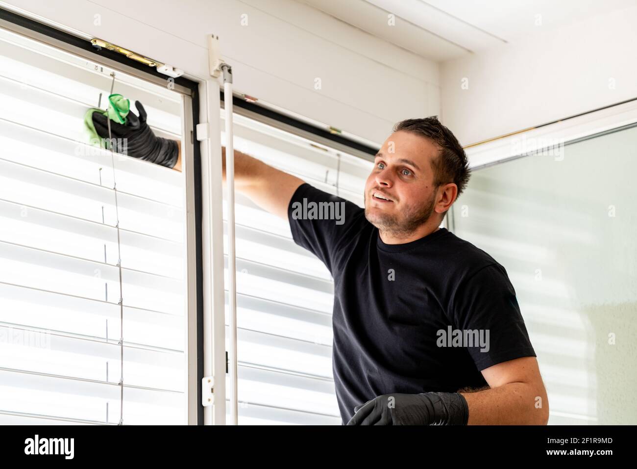 Professionelle Reinigung Fensterläden in einer Wohnung mit einem Grünes Mikrofasertuch Stockfoto