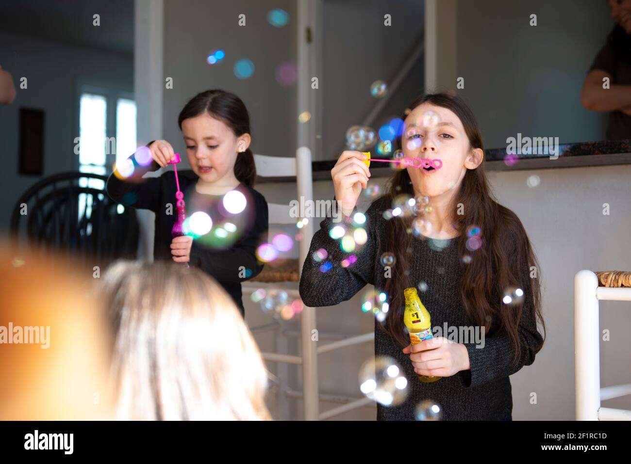 Nette kleine Mädchen Blasen in der Küche mit ihrer Familie. Stockfoto