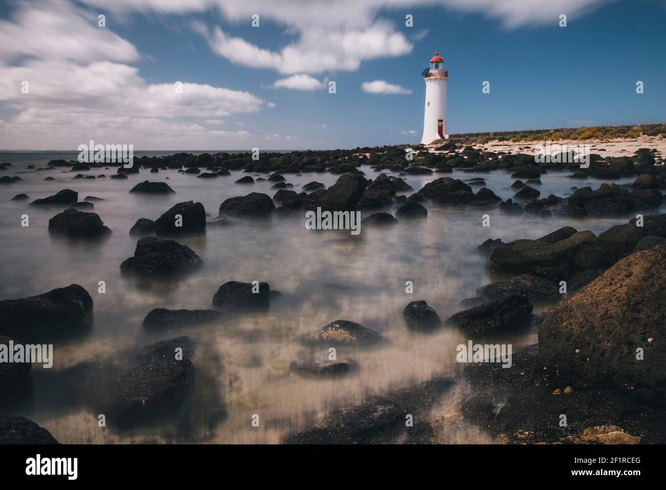 Port Fairy Lighthouse auf Griffiths Island, Ebbe im Vordergrund, Wellen im Hintergrund, Victoria, Australien. Stockfoto