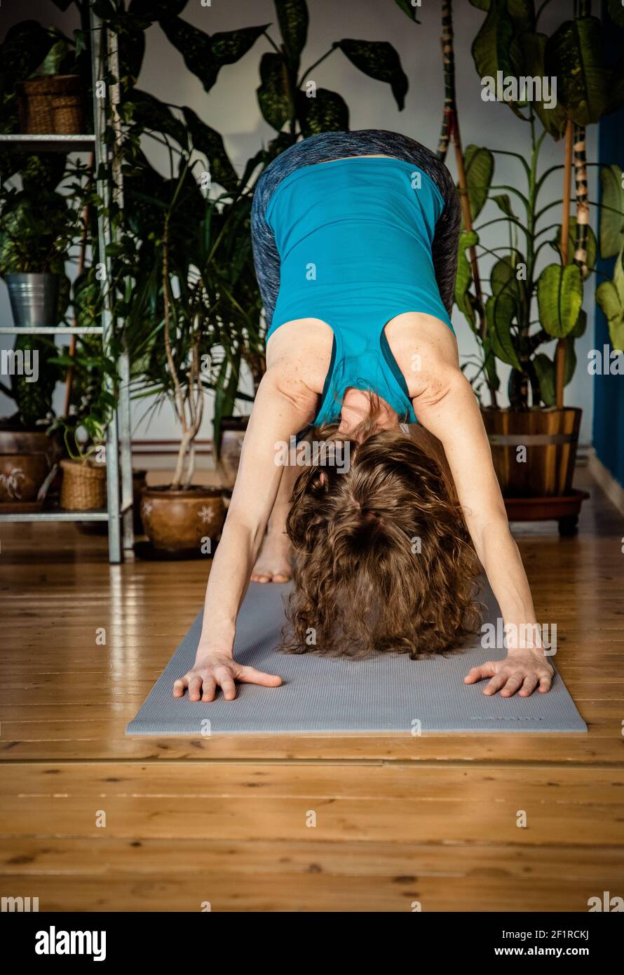 Frau macht Yoga zu Hause Zimmerpflanzen im Hintergrund Stockfoto