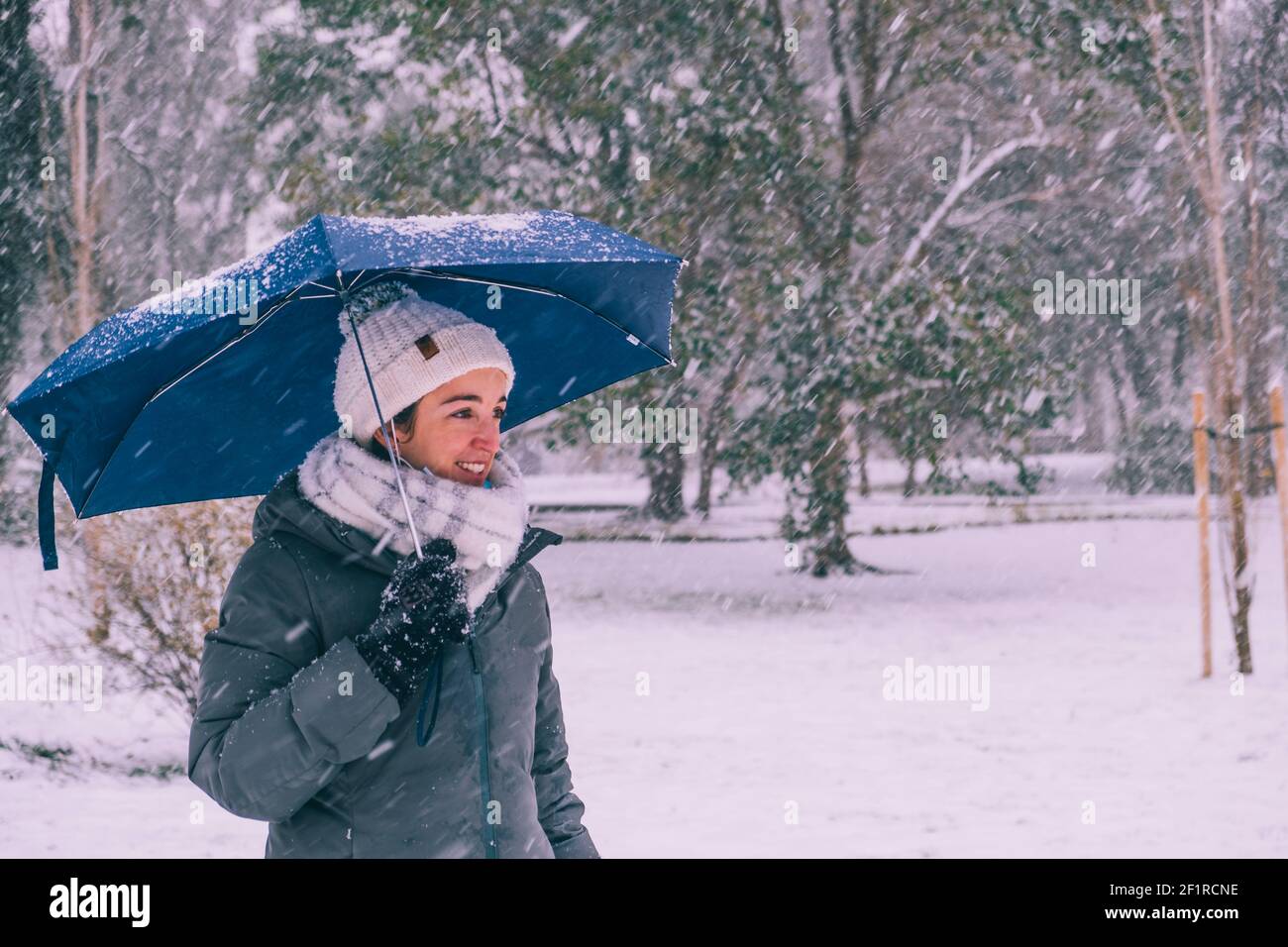 Glückliche junge Frau unter dem Dach genießen Filomena Schneesturm im Retiro Park, Madrid, Spanien Stockfoto