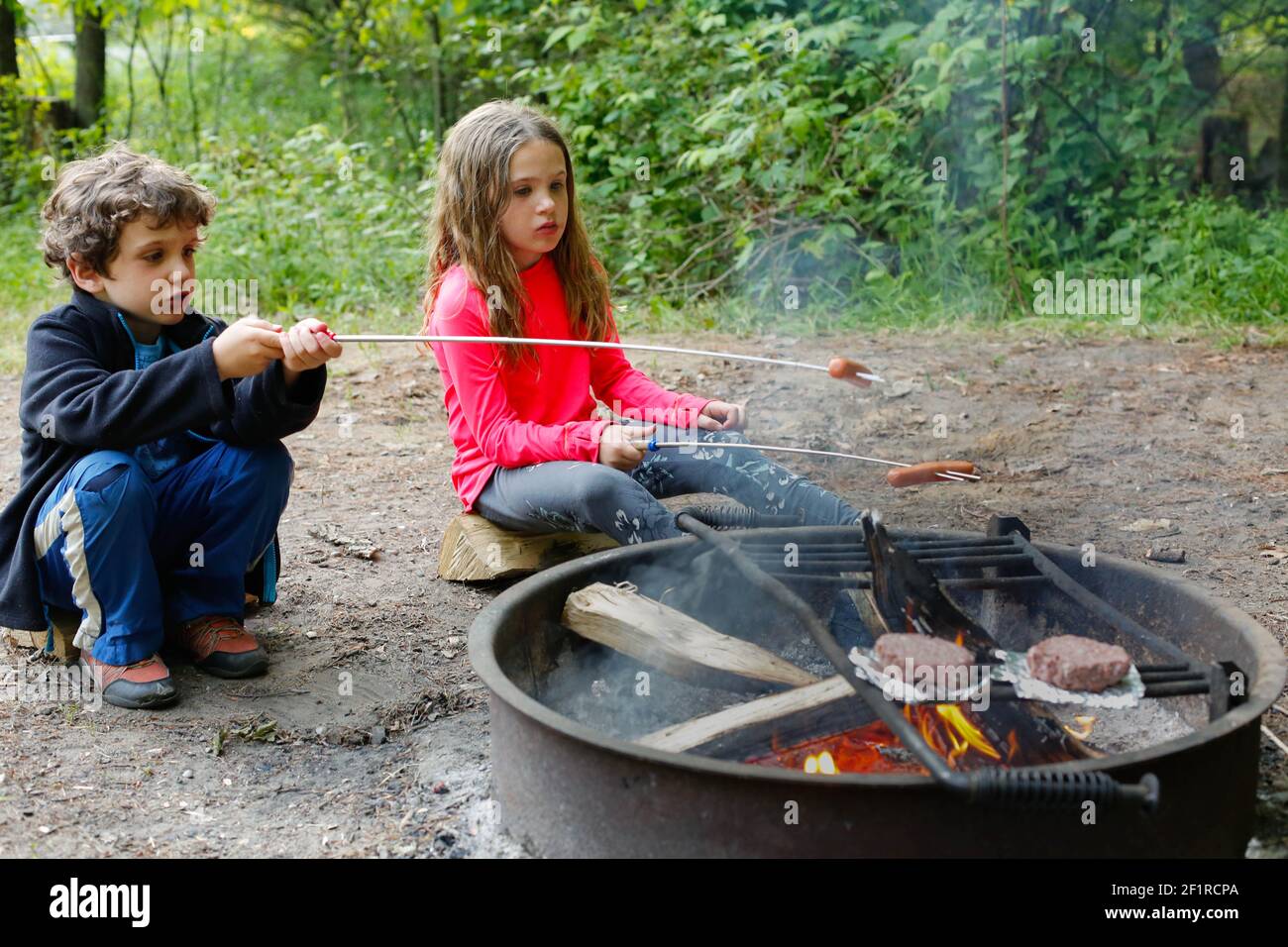 Zwei Kinder, die während des Campens Hot Dogs rösten Stockfoto