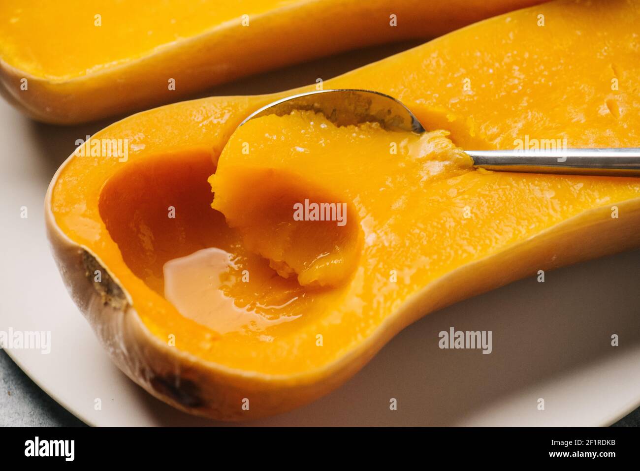 Aushöhlung langsam gekochter Butternusskürbis mit einem Löffel Stockfoto