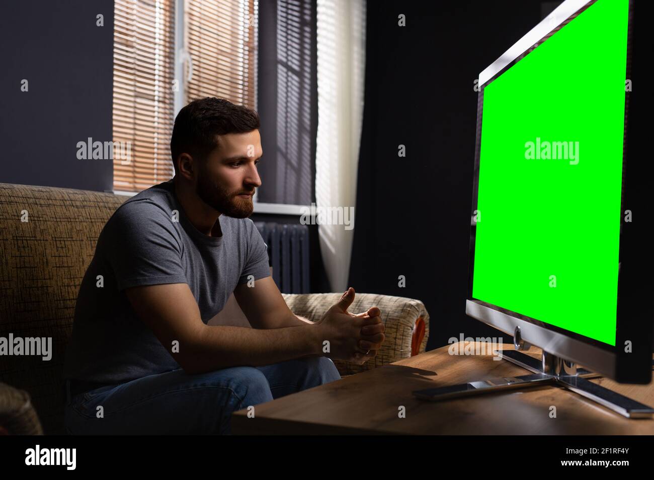 Profilfoto eines jungen, gutaussehenden Mannes in legerer Kleidung, in der Freizeit, beim Fernsehen in seinem Luxushaus. Freizeit nach der Arbeit. Mock Stockfoto