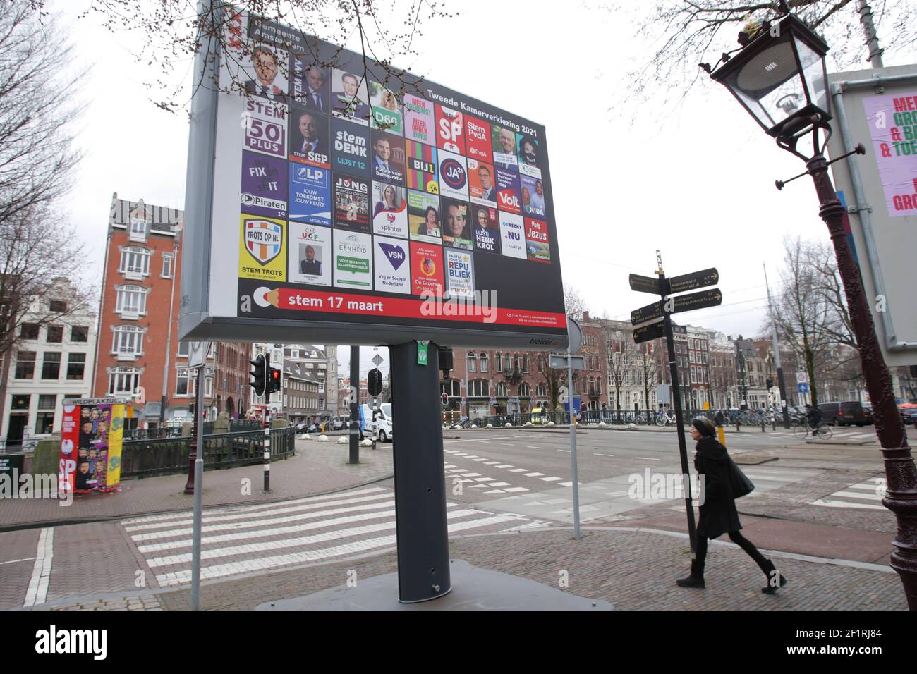 Eine Frau kommt an einem Plakat vorbei, auf dem die niederländischen politischen Parteien am 9. März 2021 in Amsterdam, Niederlande, die Straße der Coronavirus-Pandemie fast verlassen sehen. Die Niederlande gehen an die Wahlen, um eine neue Regierung am 17. März zu wählen. (Foto von Paulo Amorim/Sipa USA) Stockfoto