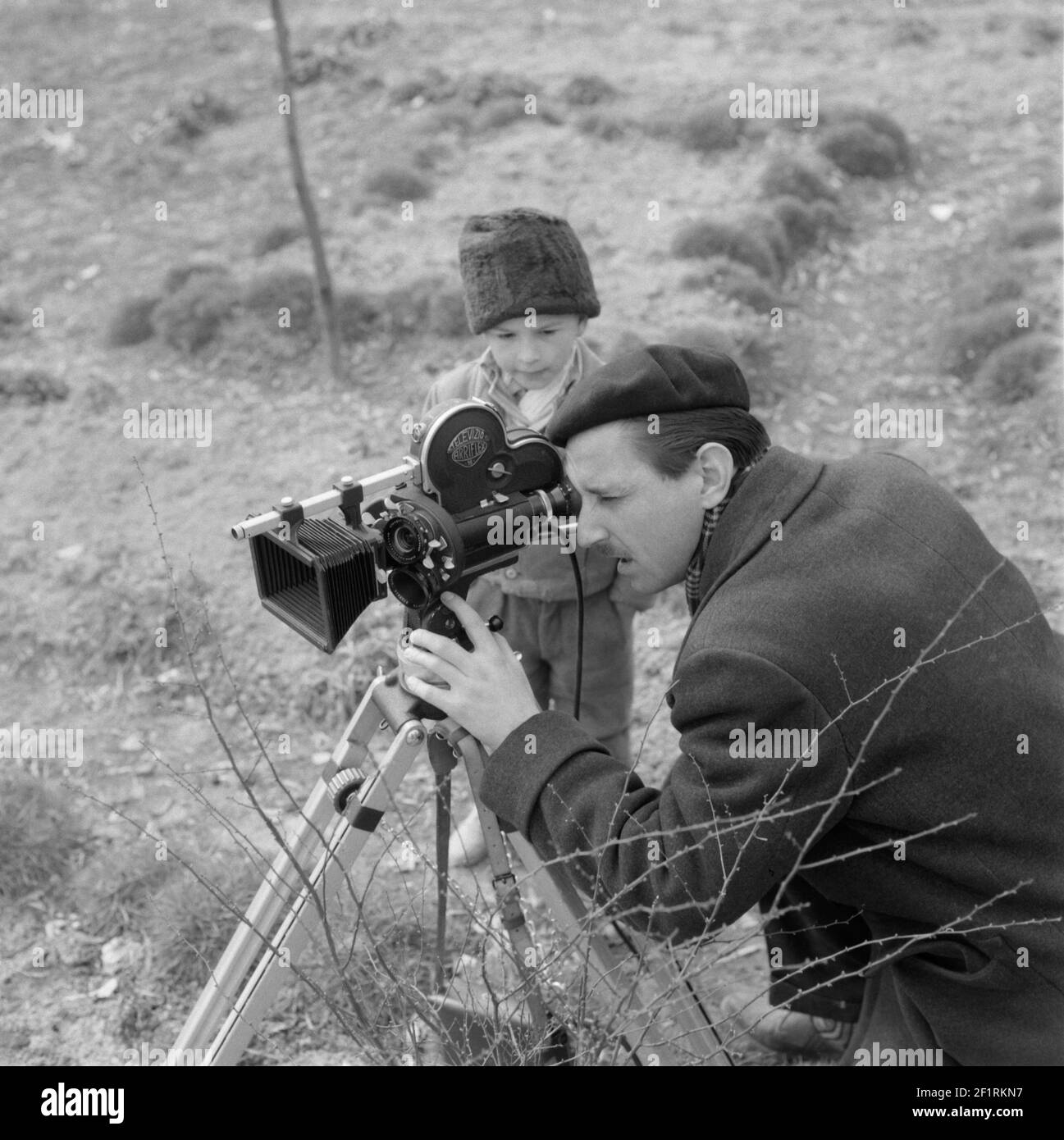 Kleiner Junge sieht Mann, der Film mit Stativ montiert filmt arriflex 16mm analoge Filmkamera 1960s ungarn Stockfoto