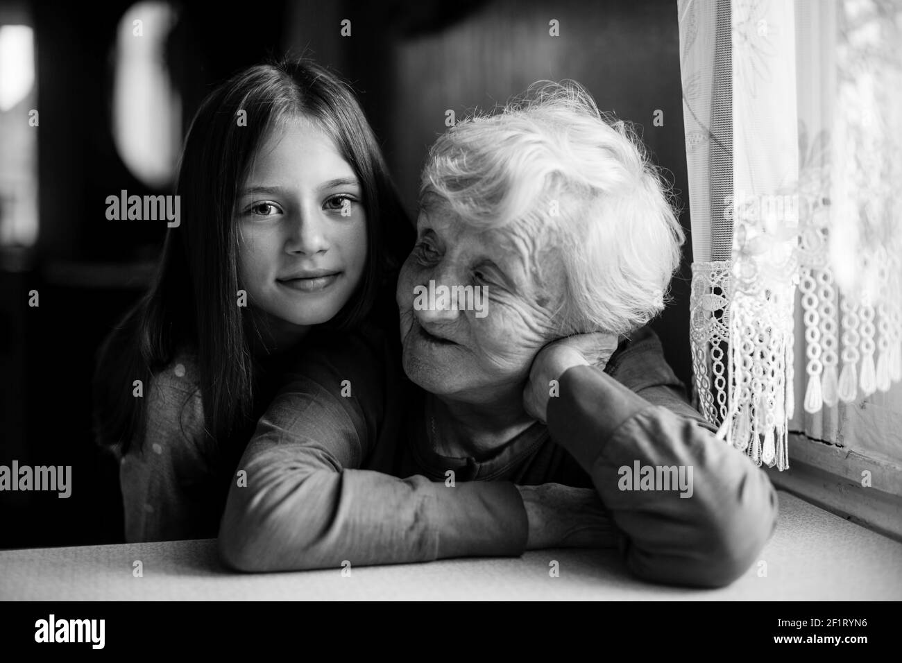 Kleines Mädchen umarmt ihre Großmutter. Schwarz-Weiß-Porträt. Stockfoto