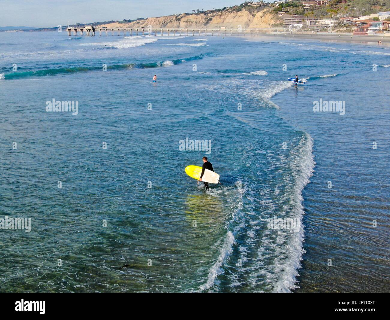 Surfer im Nassanzug mit einem gelben Surfbrett auf dem Strand Stockfoto