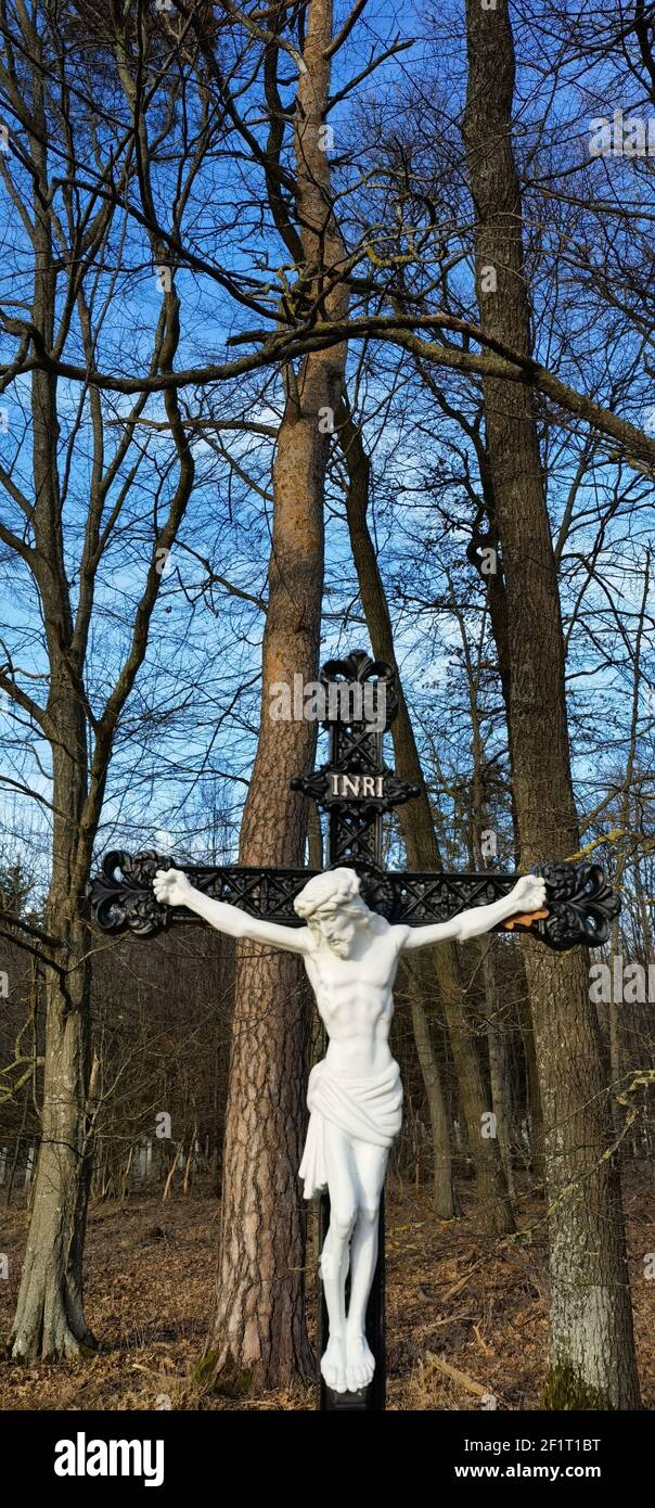 Kreuz und Jesus Christus Statue auf Wald Hintergrund. Religiöses Symbol. Katholizismus und Christentum Konzept.Denkmäler und Statuen in Europa. Friedhof Stockfoto